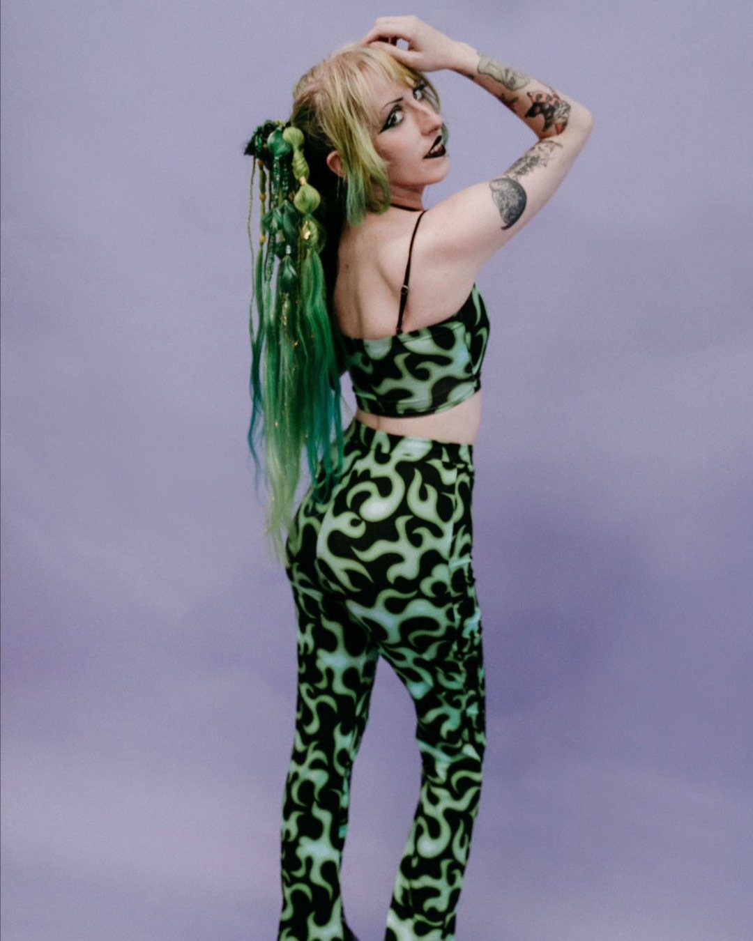 8 Plus Size Rave Outfits That Bring the Energy 1 Person in green and black psychedelic print crop top and matching leggings.