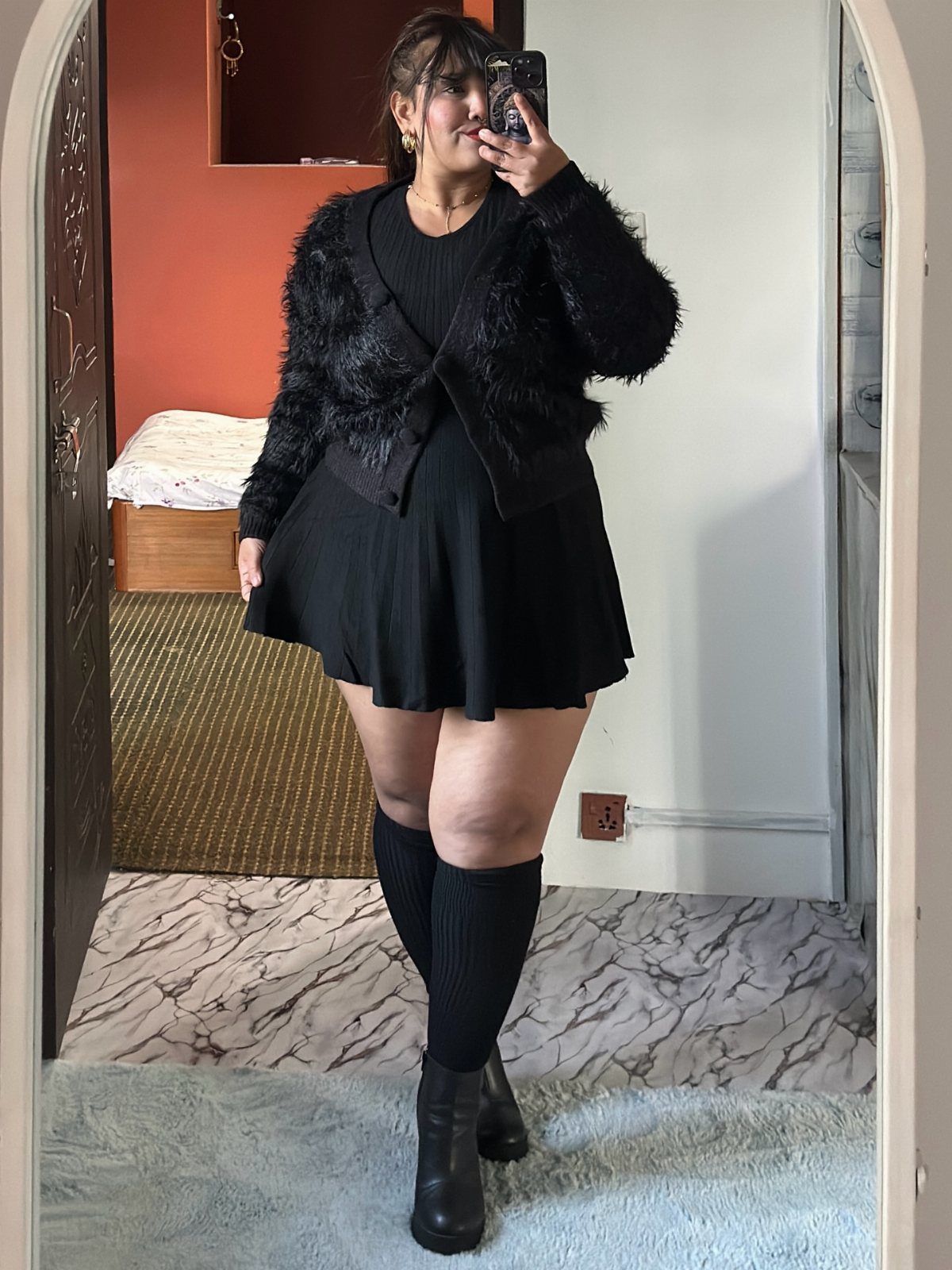 Plus Size Winter Outfits: 7 Cozy and Stylish Looks to Try 3 Plus-size woman in a black fuzzy cardigan, black dress, and knee-high socks.
