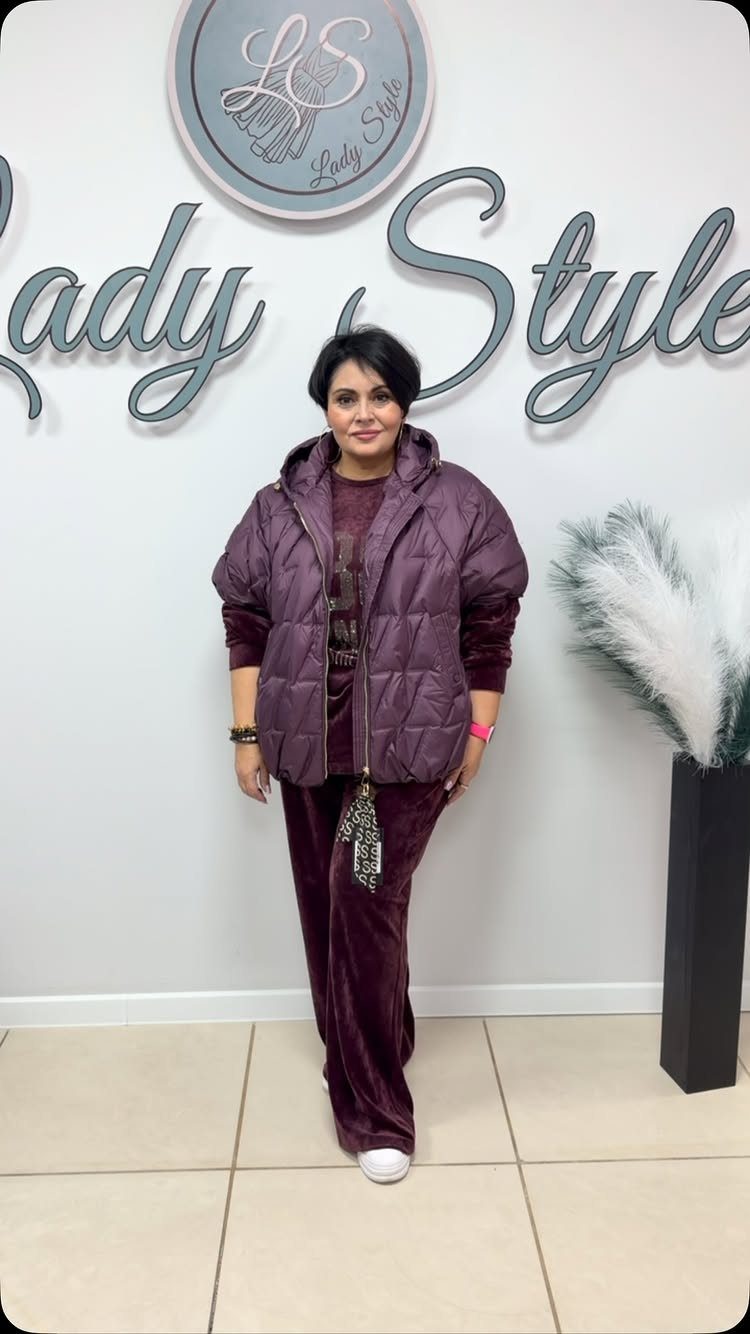 Plus Size Winter Outfits: 7 Cozy and Stylish Looks to Try 7 Plus-size woman wearing a plum puffer jacket and matching velvet tracksuit in a studio.
