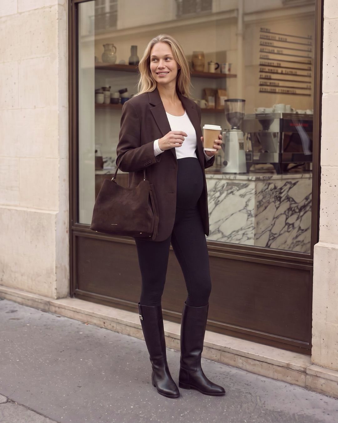 12 Pregnant Fall Outfits That Work Through Every Trimester 8 Pregnant woman wearing a brown blazer, white top, black leggings, and tall black boots.