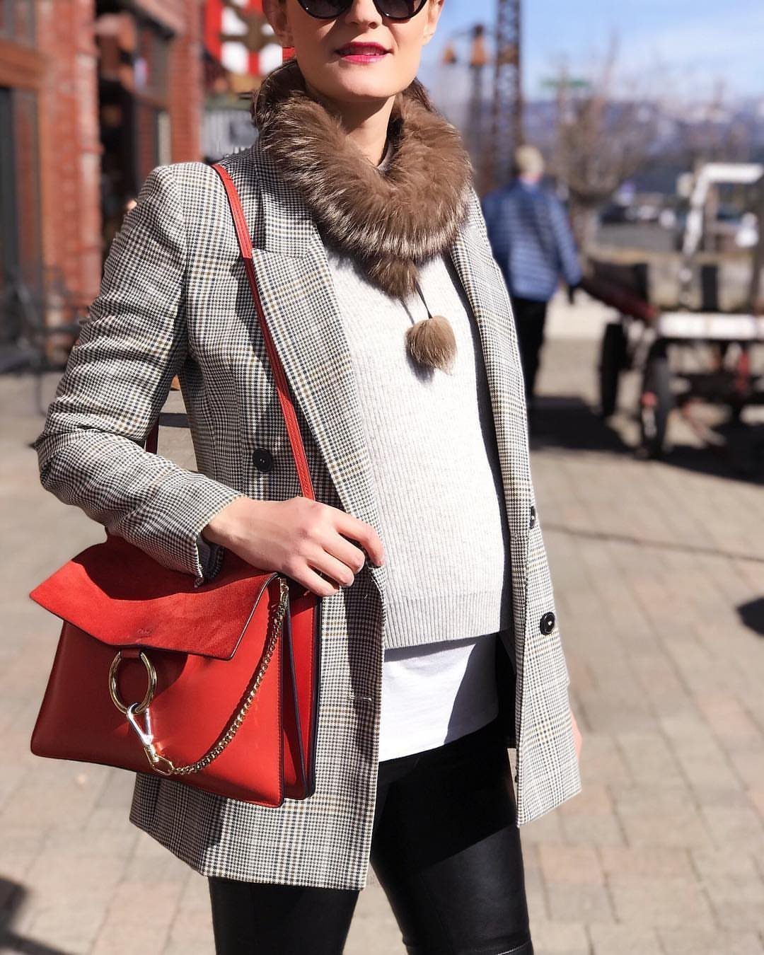 12 Pregnant Fall Outfits That Work Through Every Trimester 11 Pregnant woman in a plaid blazer, grey sweater, and black leather-look leggings.