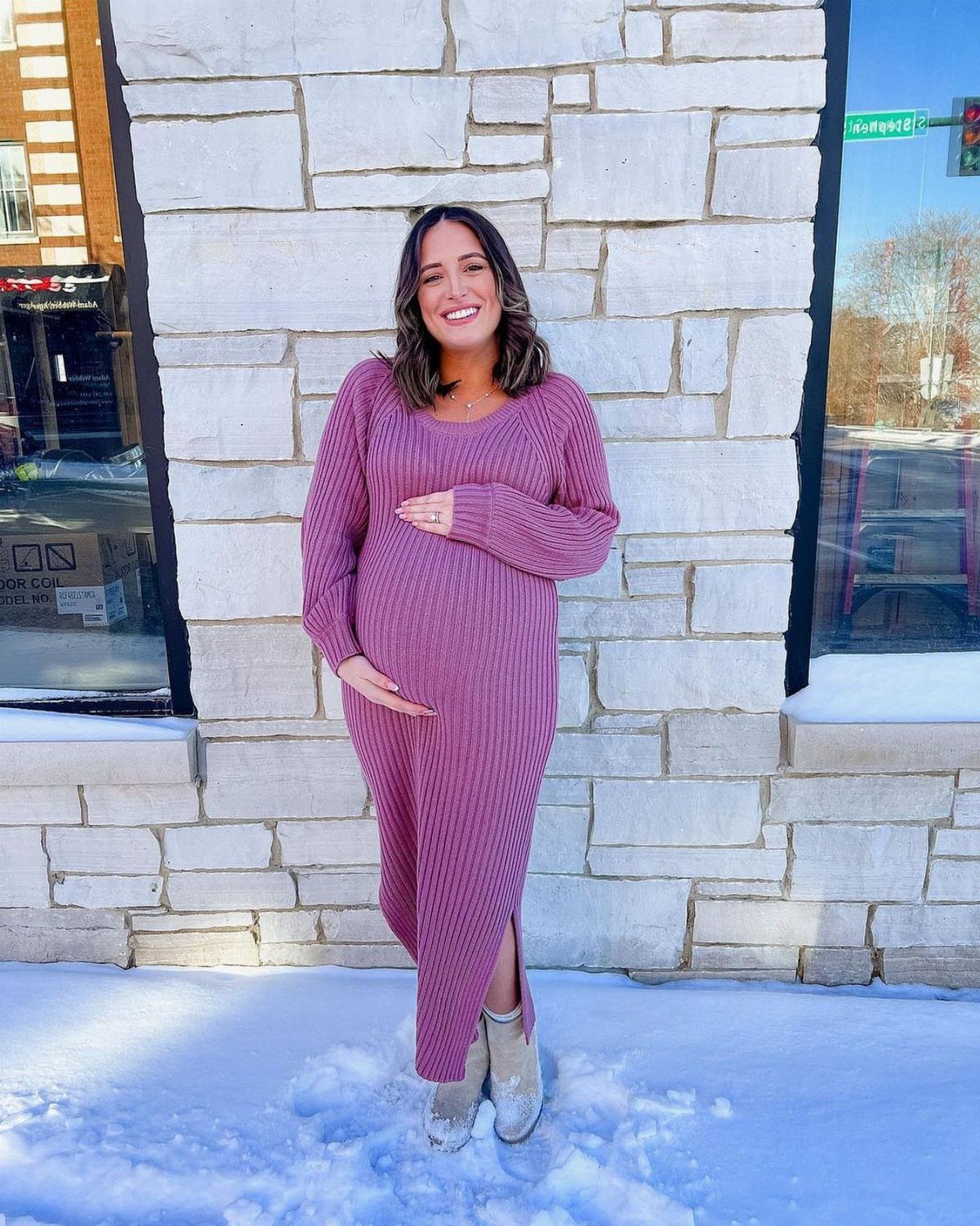 12 Pregnant Fall Outfits That Work Through Every Trimester 6 Pregnant woman wearing a long purple ribbed sweater dress and light ankle boots.