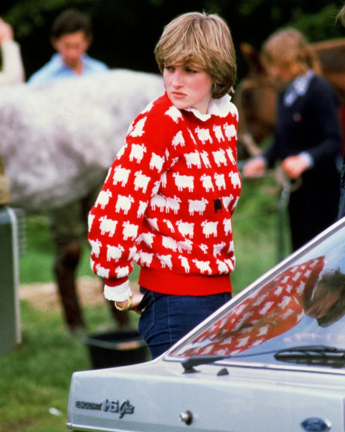 Princess Diana Outfits That Defined Royal Style (11 Ideas) 7 Princess Diana wearing a red sweater with white sheep patterns and blue jeans.