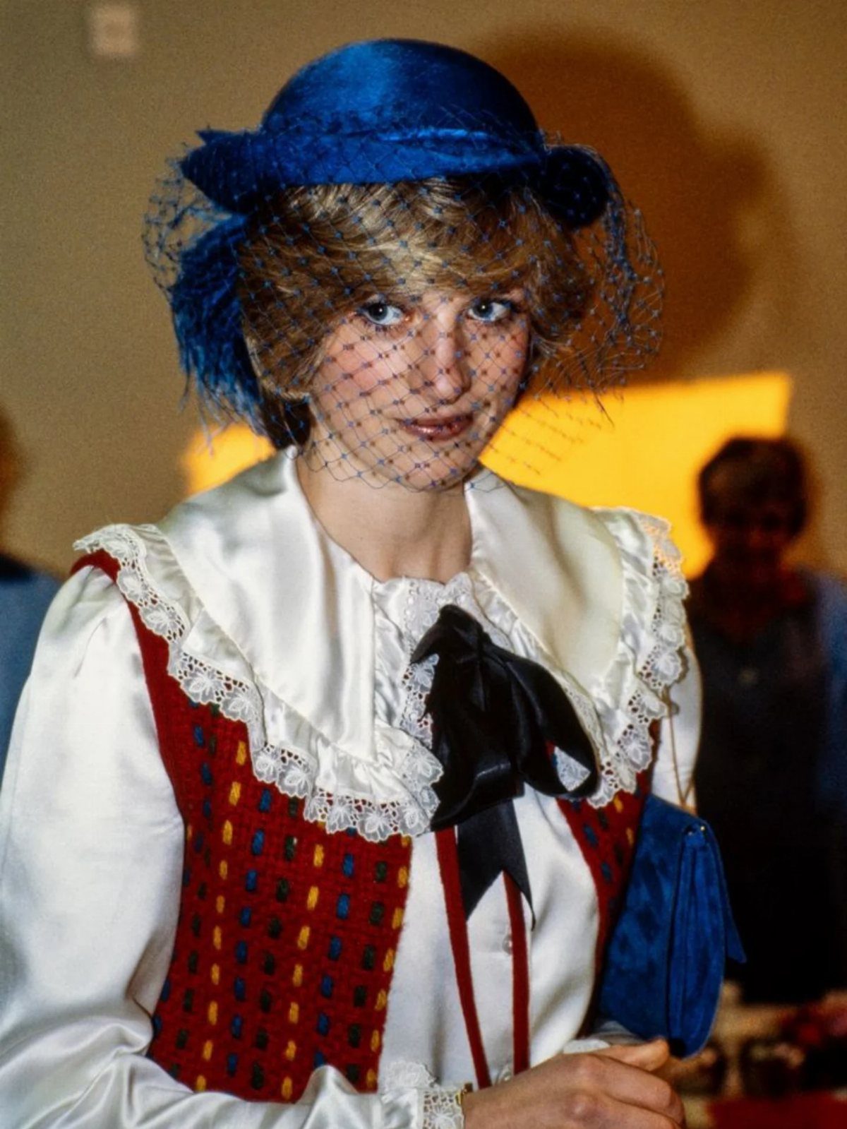 Princess Diana Outfits That Defined Royal Style (11 Ideas) 2 Princess Diana wearing a white ruffled statement blouse, red vest, and blue hat.