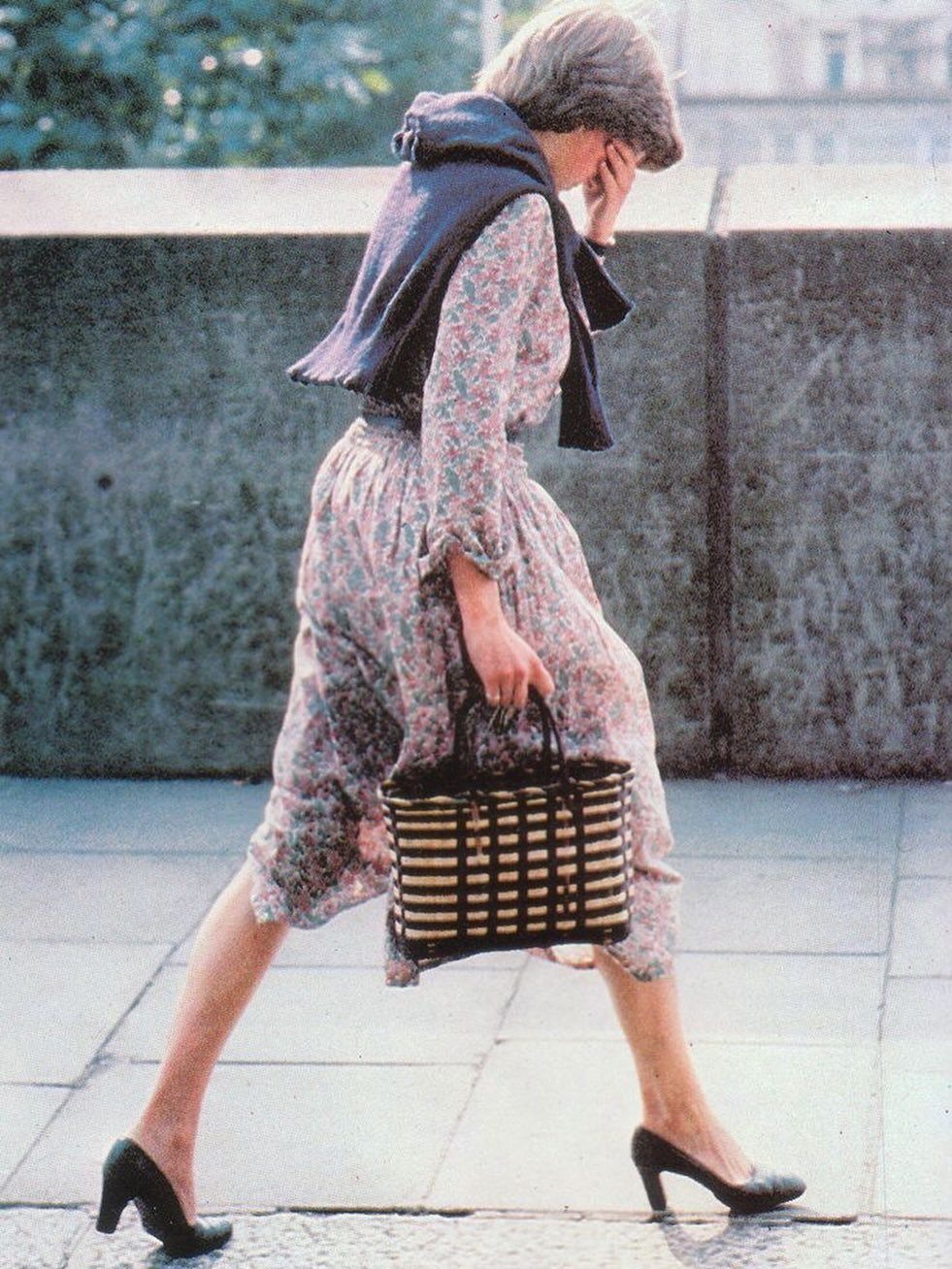 Princess Diana Outfits That Defined Royal Style (11 Ideas) 9 Princess Diana wearing a floral midi dress with a blue sweater and handbag.