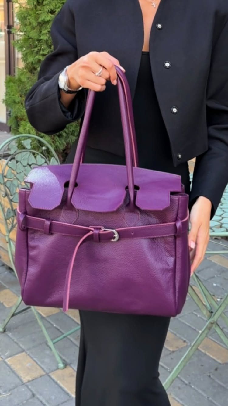 Purple Winter Outfits: 9 Ways to Style the Season's Boldest Color 4 Large purple leather handbag held by a person wearing a black blazer.