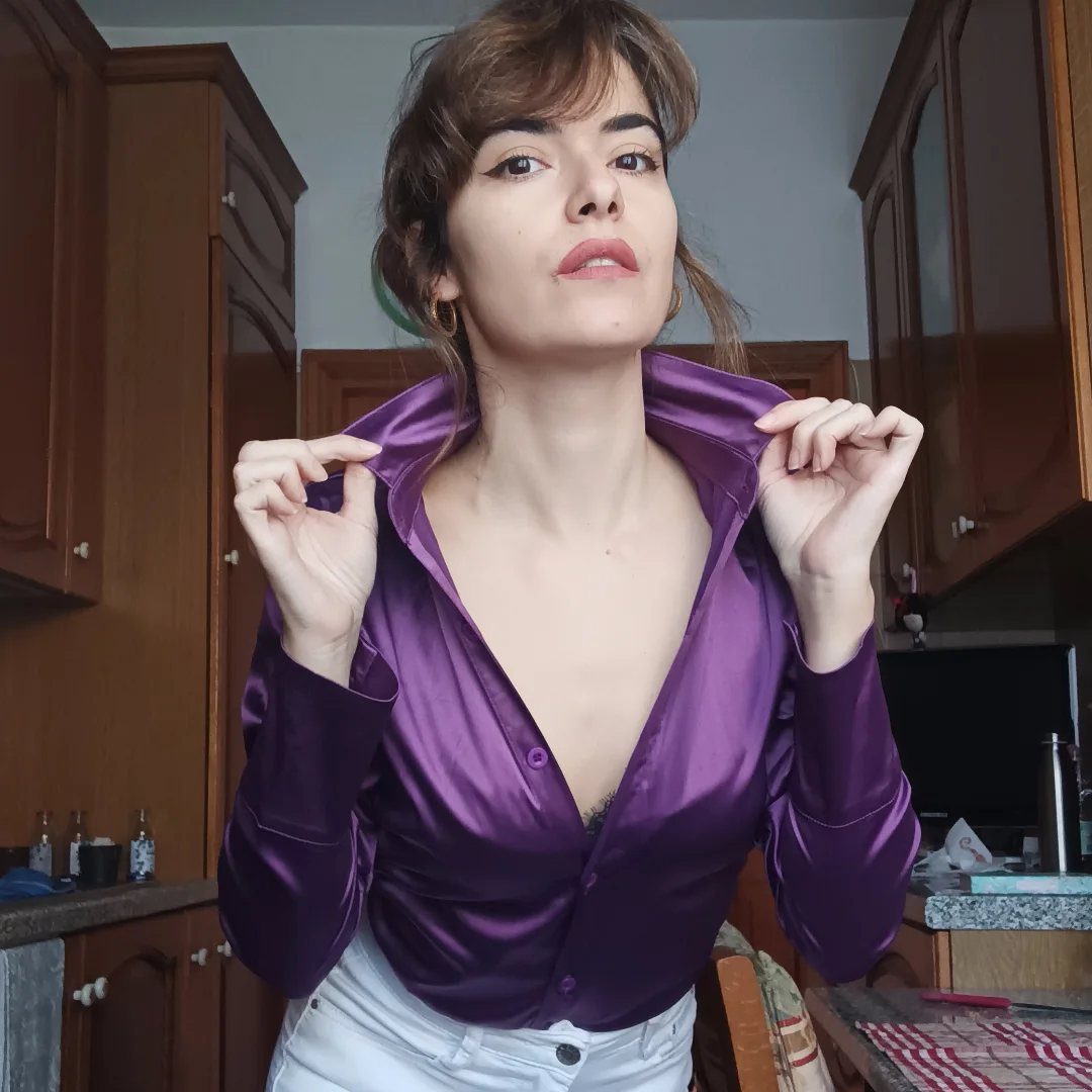 Purple Winter Outfits: 9 Ways to Style the Season's Boldest Color 6 Woman wearing a purple satin shirt and white pants in a kitchen setting.
