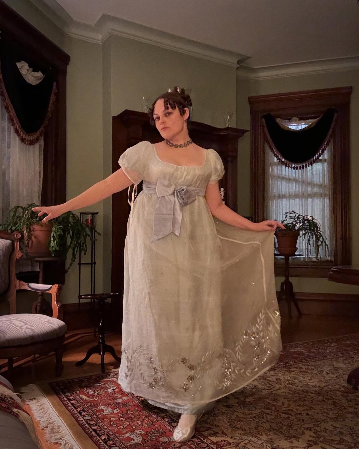 Regency Era Outfits Women Wore: 9 Elegant Period Pieces 2 Woman in a white Regency era evening gown with empire waist and silver embroidery.