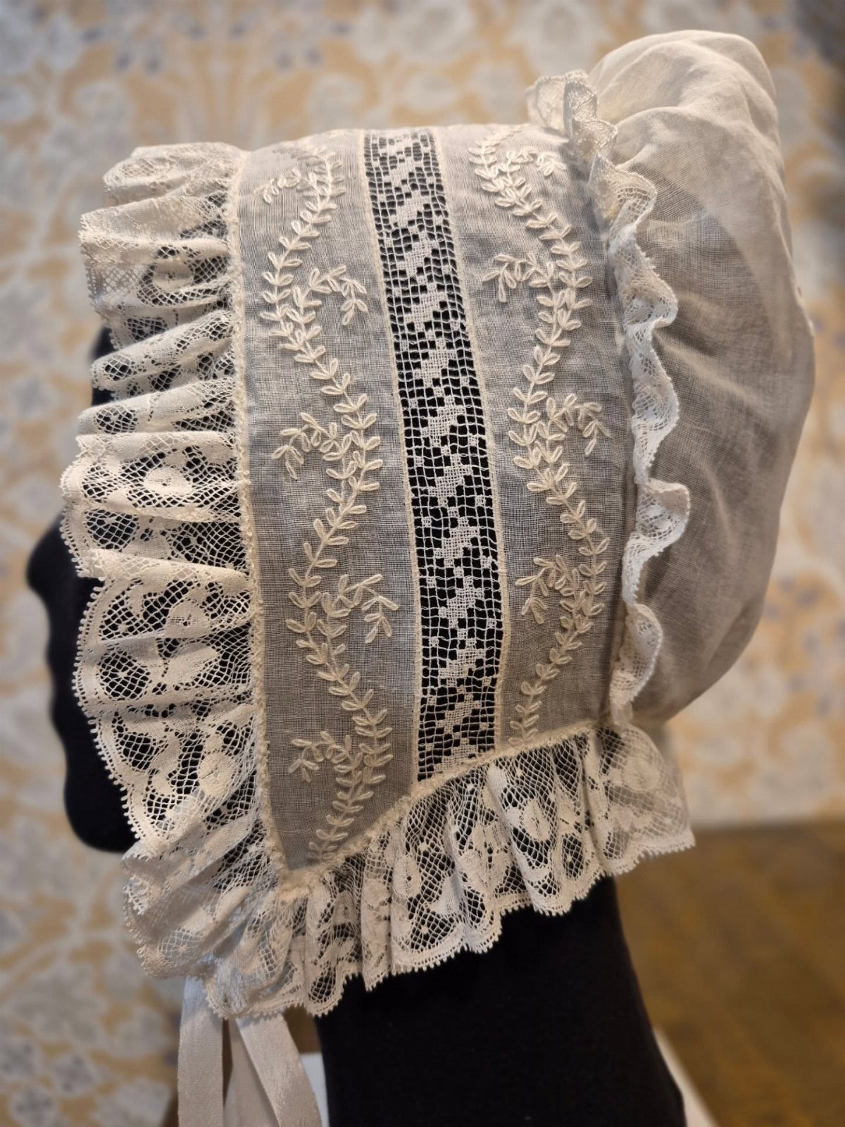 Regency Era Outfits Women Wore: 9 Elegant Period Pieces 7 White Regency era mob cap with lace ruffles and floral embroidery on a mannequin.
