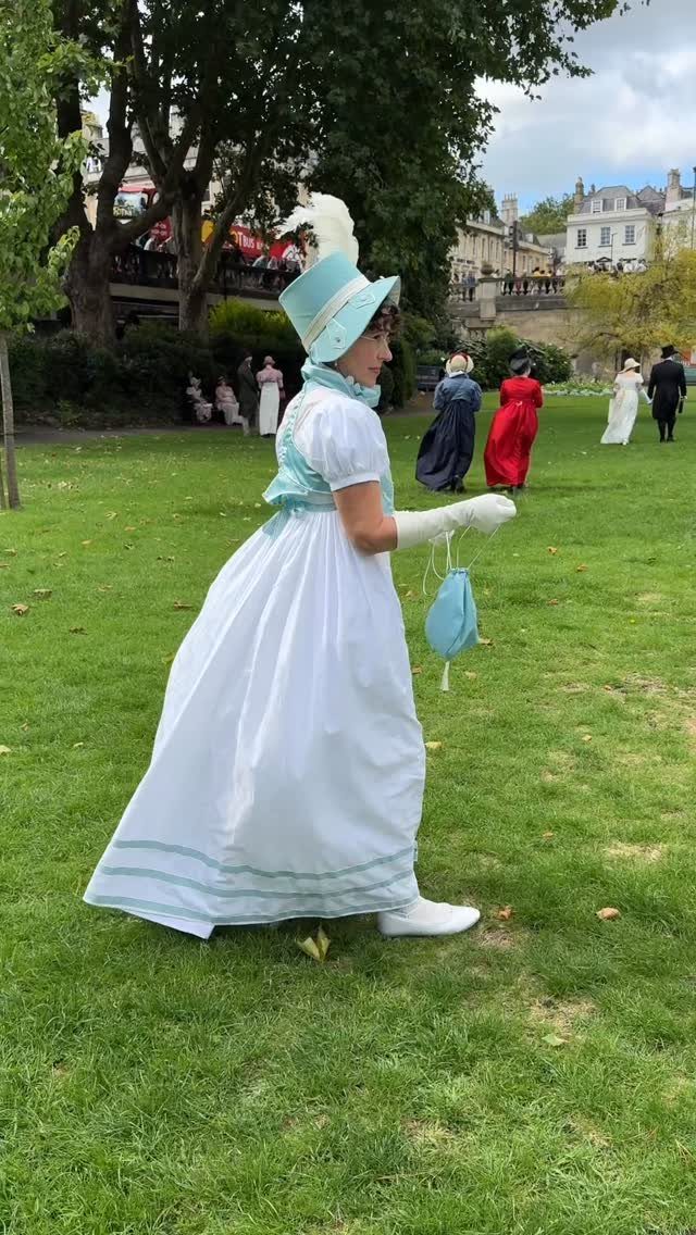 Regency Era Outfits Women Wore: 9 Elegant Period Pieces 9 Woman wearing a white and light blue Regency era dress and hat outdoors.