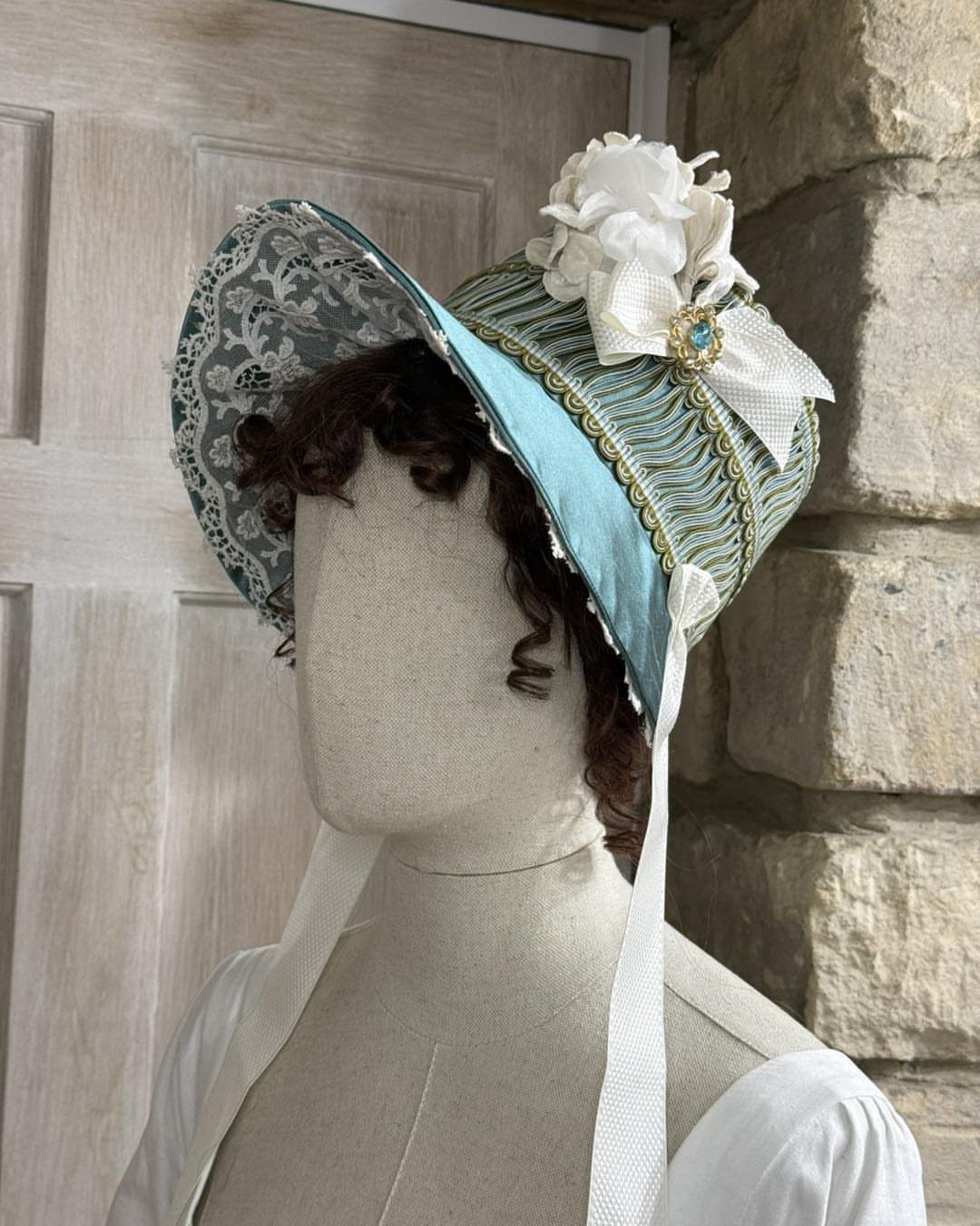 Regency Era Outfits Women Wore: 9 Elegant Period Pieces 8 Regency era woman's straw hat with teal ribbon and white flower on a mannequin