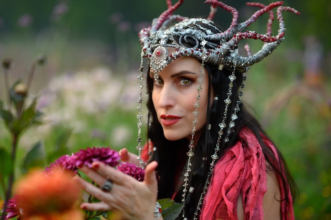 Renaissance Fair Outfits Women Can Wear: 12 Looks 5 Woman wearing an ornate silver antler crown and red clothing in a flower garden