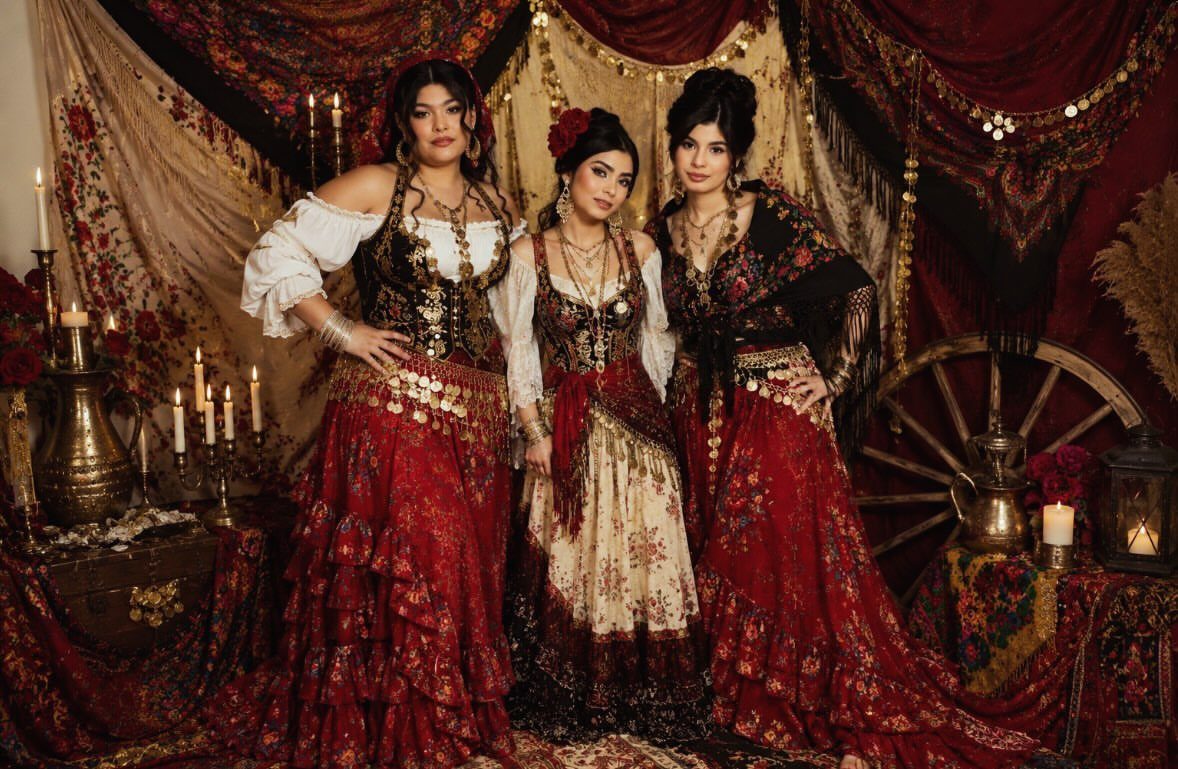 Renaissance Fair Outfits Women Can Wear: 12 Looks 4 Three women wearing bold, colorful gypsy-style Renaissance costumes with layered red skirts and jewelry.