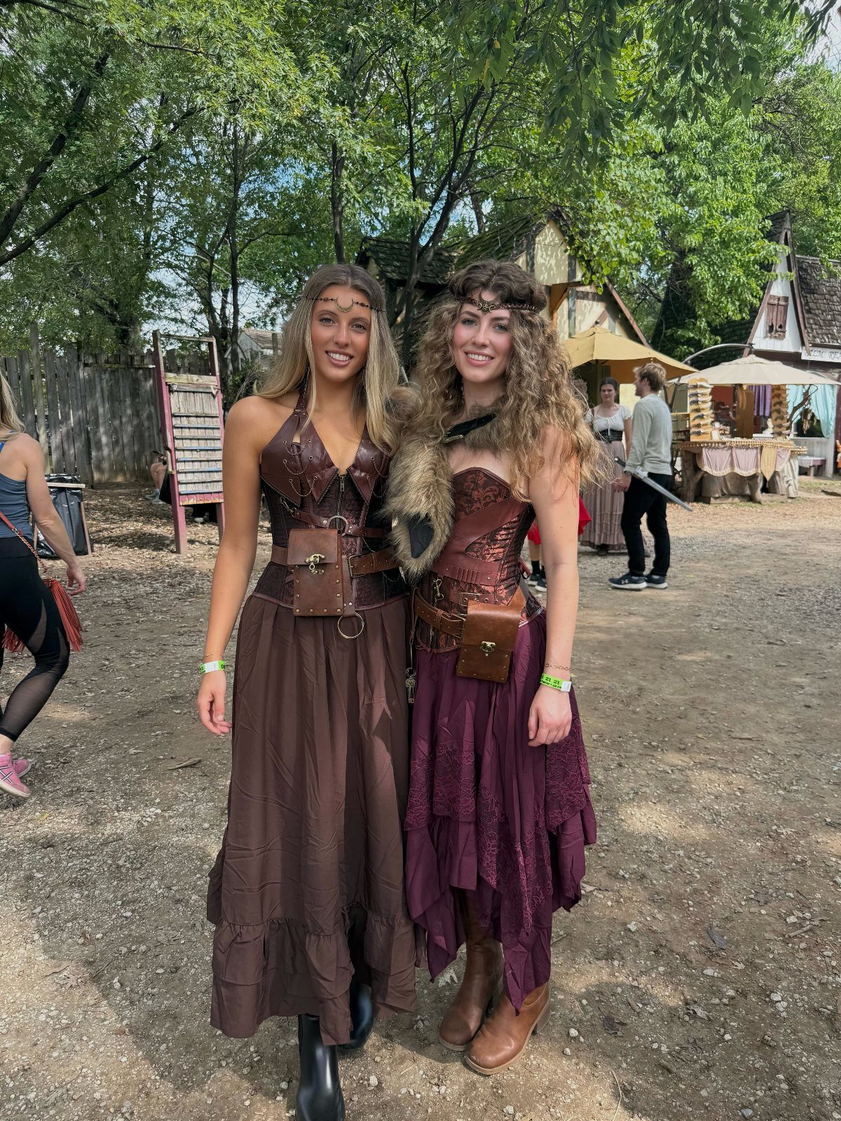Renaissance Festival Outfits: 8 Ideas from Peasant to Princess 2 Two women wearing brown and burgundy renaissance festival outfits with corsets and pouches.