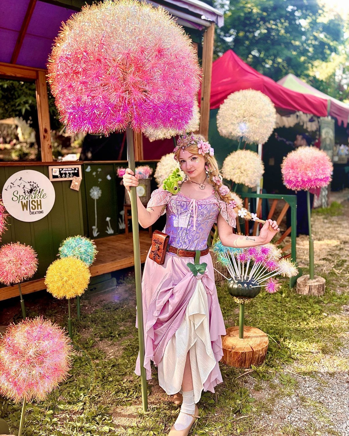 Renaissance Festival Outfits: 8 Ideas from Peasant to Princess 5 Woman in a pink and purple fairy outfit with a floral crown among giant colorful pom-poms.