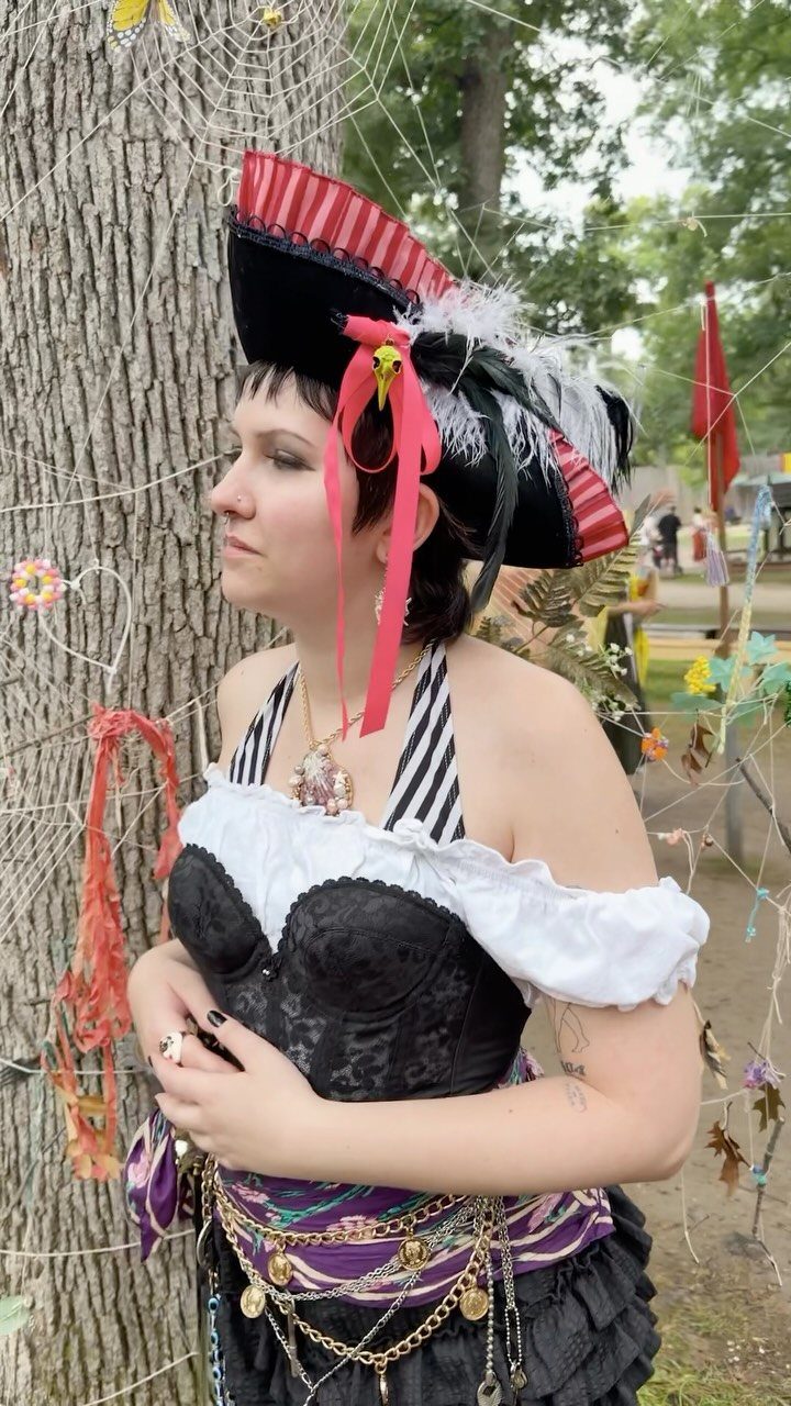 Renaissance Festival Outfits: 8 Ideas from Peasant to Princess 8 Woman in pirate outfit with tricorne hat, black corset, and gold coin belt.