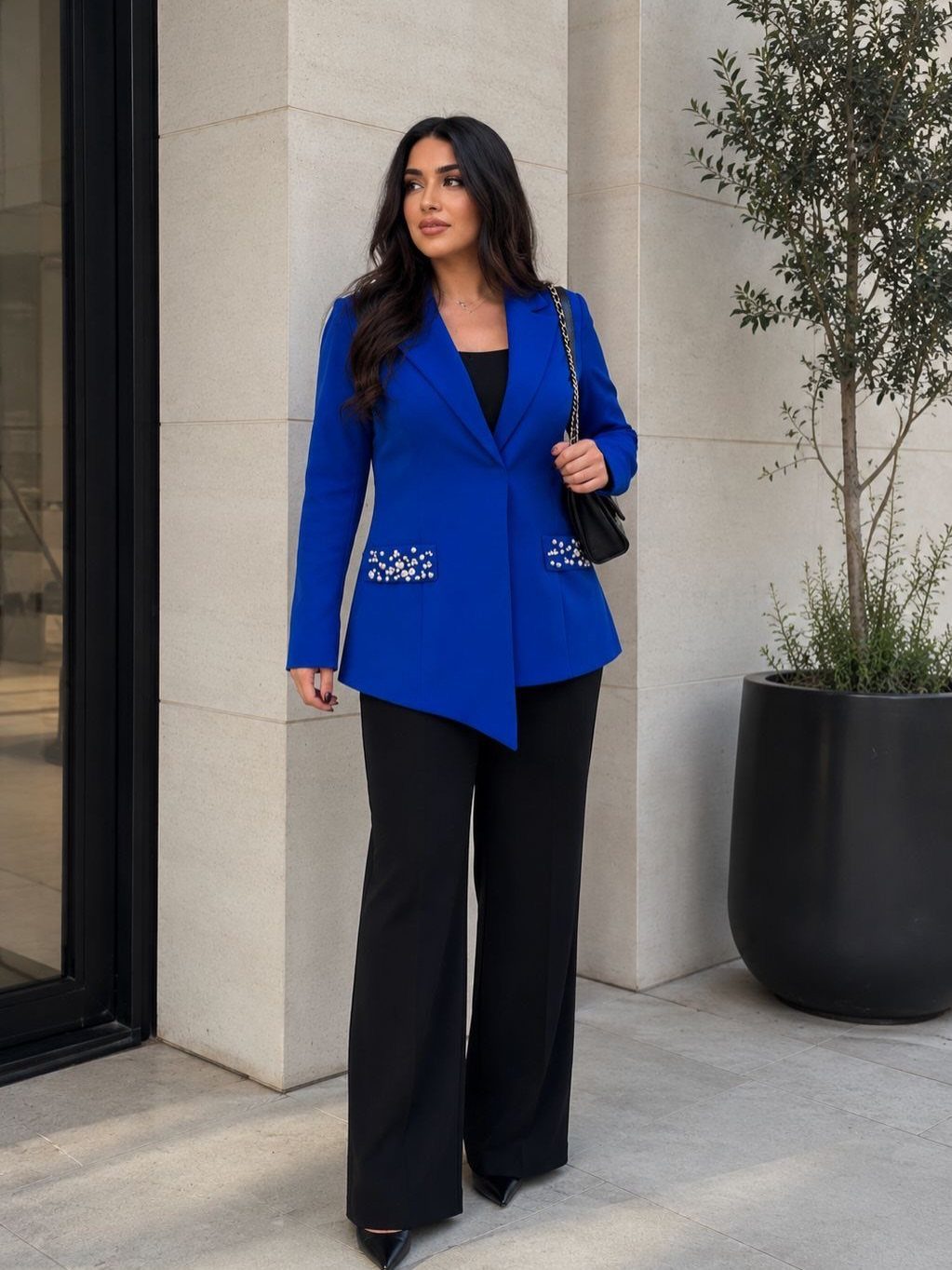 Royal Blue Outfits in 8 Styles for Every Occasion 1 Woman wearing a royal blue blazer and black wide-leg trousers standing outdoors.