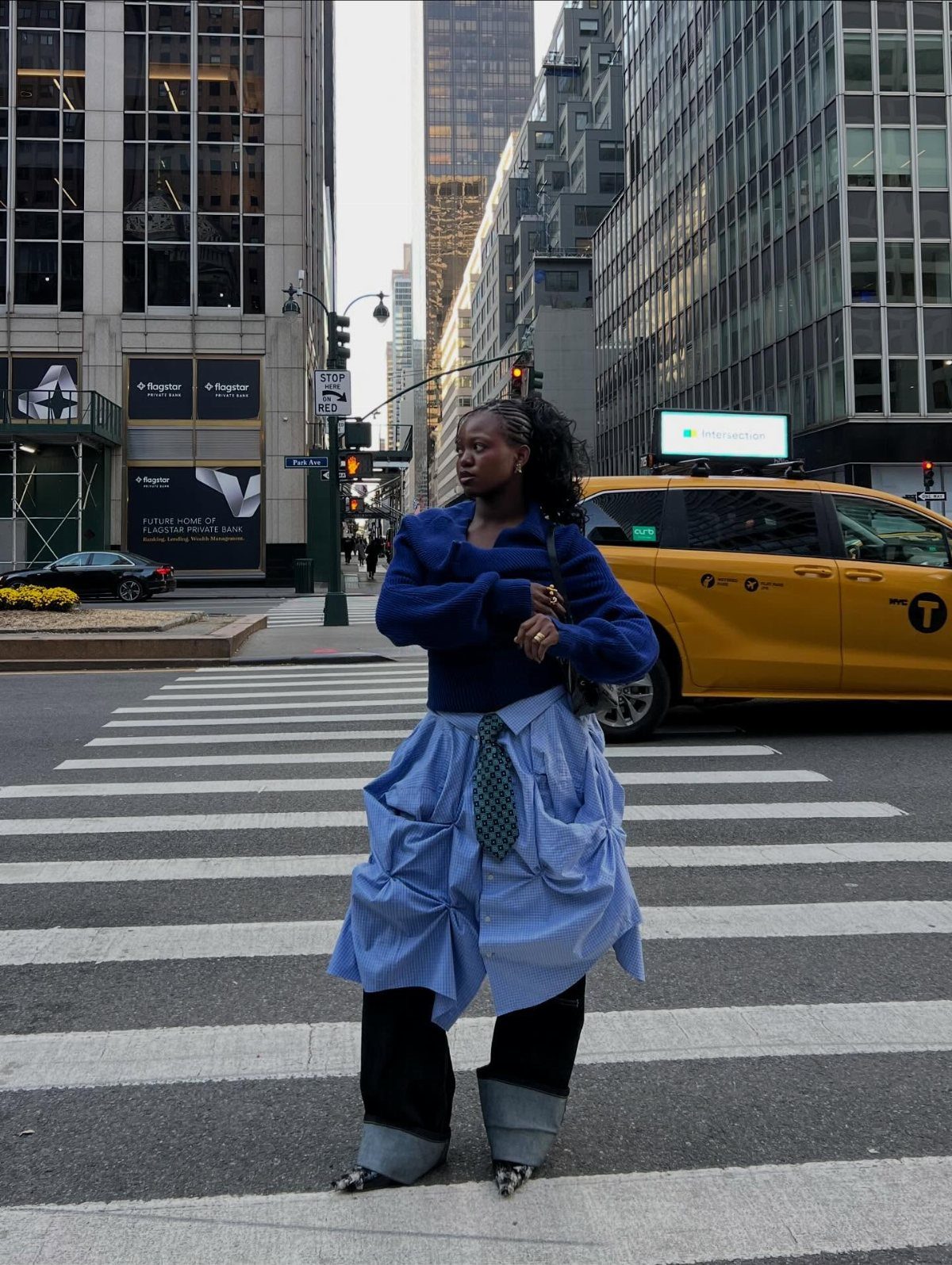 Royal Blue Outfits in 8 Styles for Every Occasion 6 Woman in royal blue sweater and striped skirt standing on a city street.