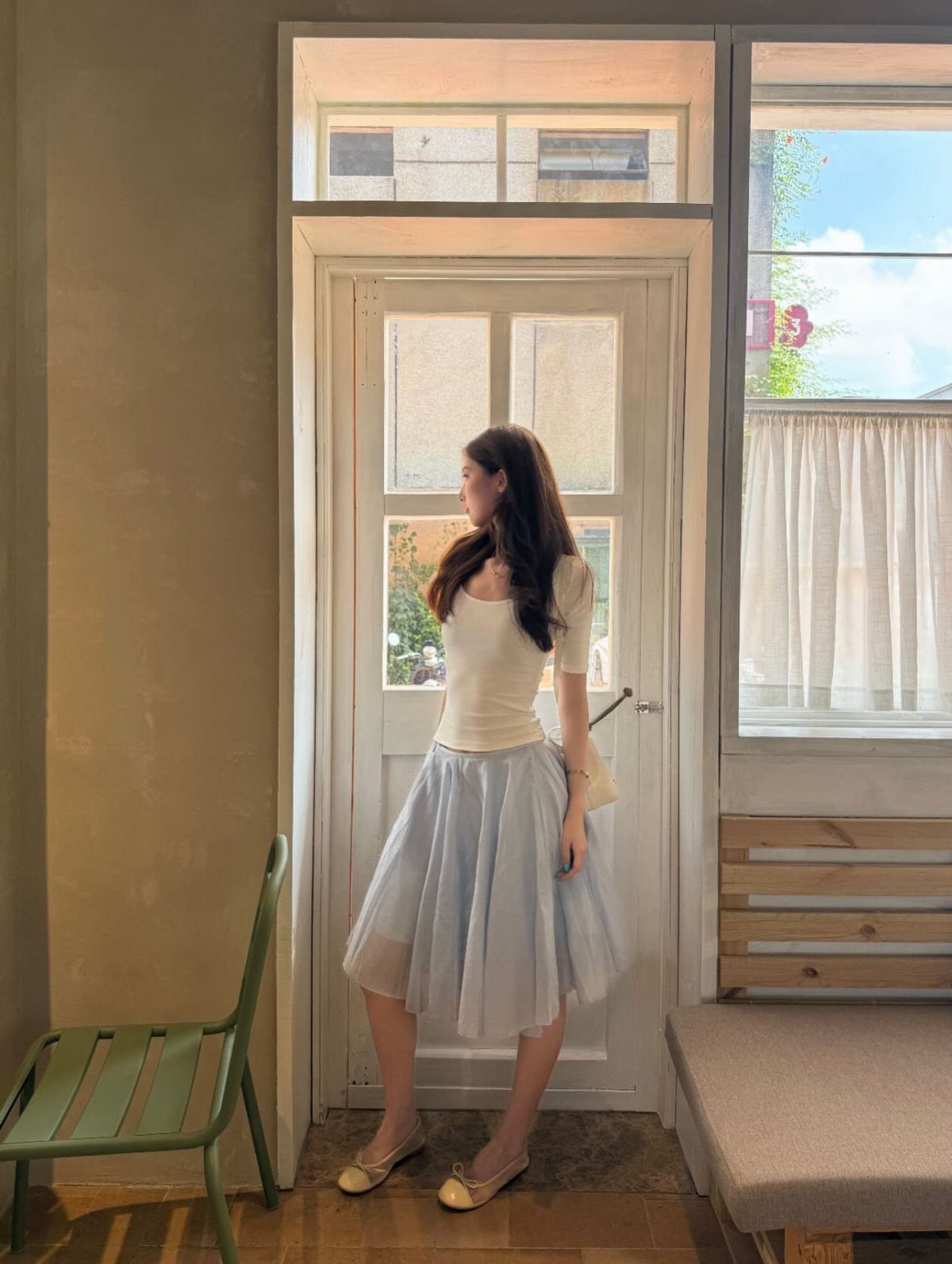 16 Short Torso Outfits That Balance Your Proportions 15 Woman wearing a white top and light blue tulle skirt standing by a door