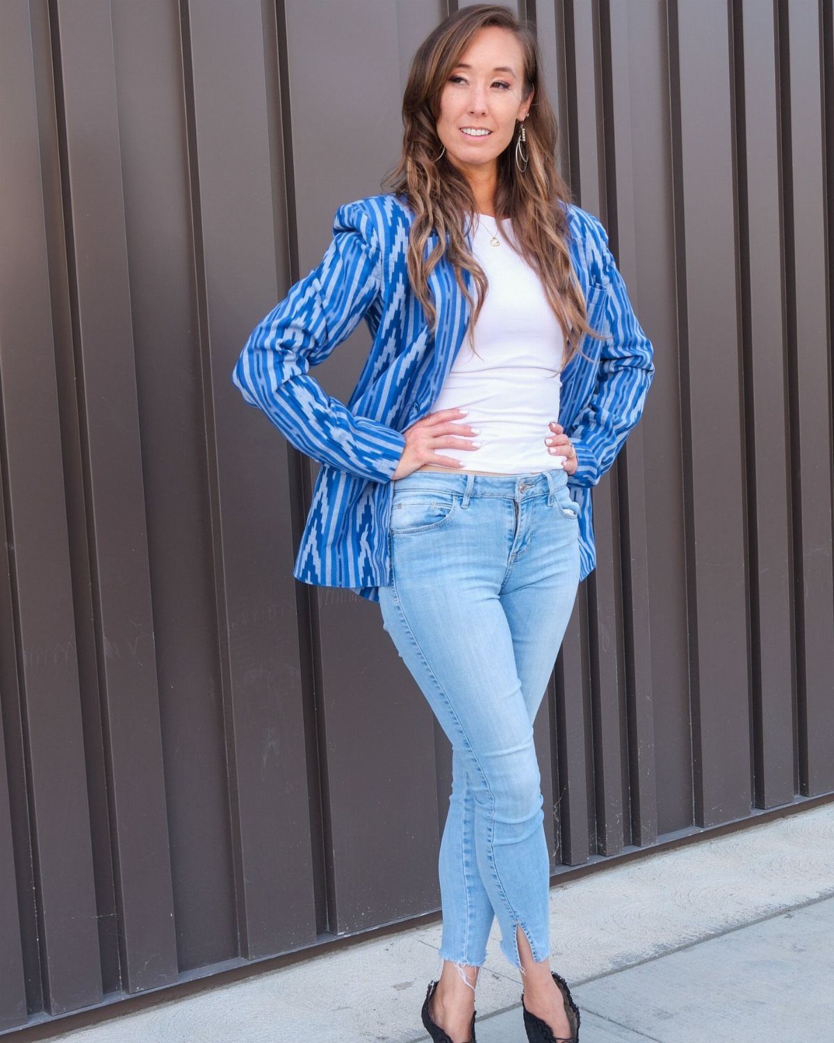 12 Spring Work Outfits That Work From Desk to Dinner 4 Woman wearing a blue patterned blazer, white top, and light blue jeans.