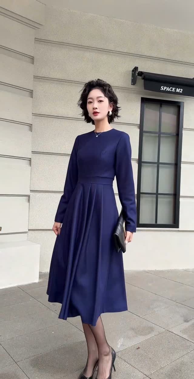 12 Spring Work Outfits That Work From Desk to Dinner 2 Woman in a navy blue long-sleeved midi dress with black heels and clutch.