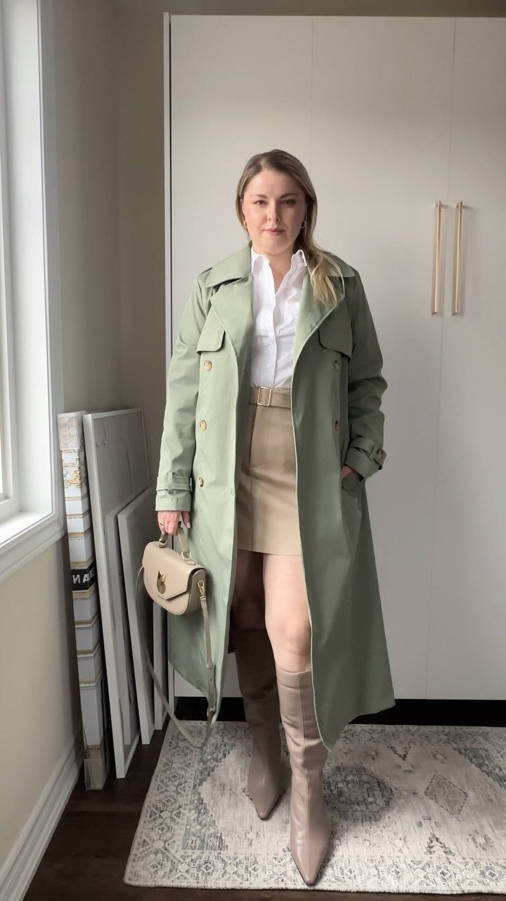 12 Spring Work Outfits That Work From Desk to Dinner 3 Woman wearing a light green trench coat, white shirt, beige skirt and boots.