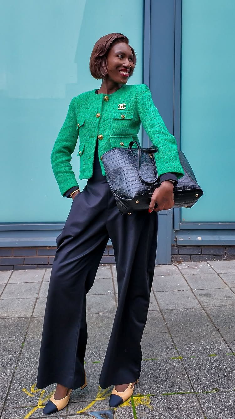 12 Spring Work Outfits That Work From Desk to Dinner 5 Woman in green cropped jacket and wide-leg black trousers holding a black leather handbag.