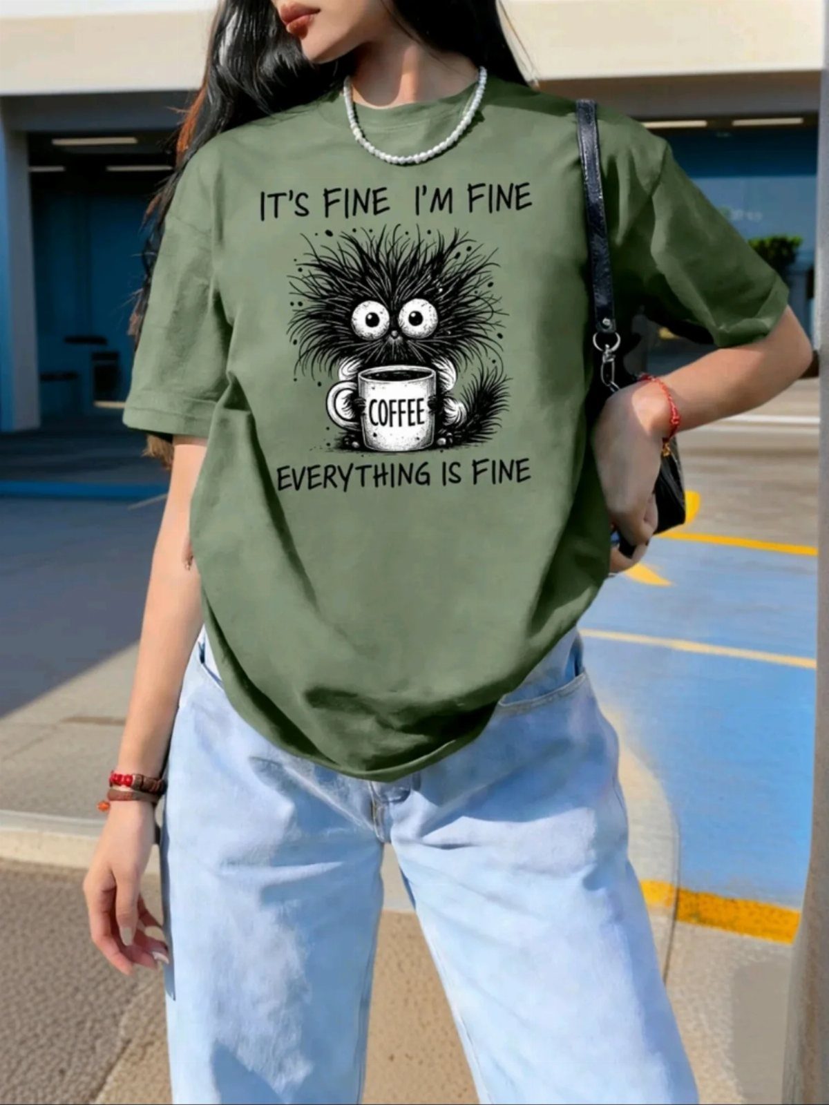 Person wearing an oversized olive green graphic t-shirt and light blue denim jeans.