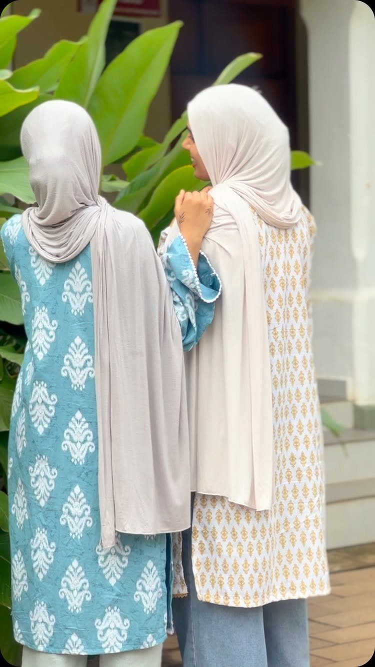 8 Summer Hijab Outfits for Modest, Breathable Style 5 Two women wearing patterned cotton kurta sets and hijabs standing outdoors near plants.