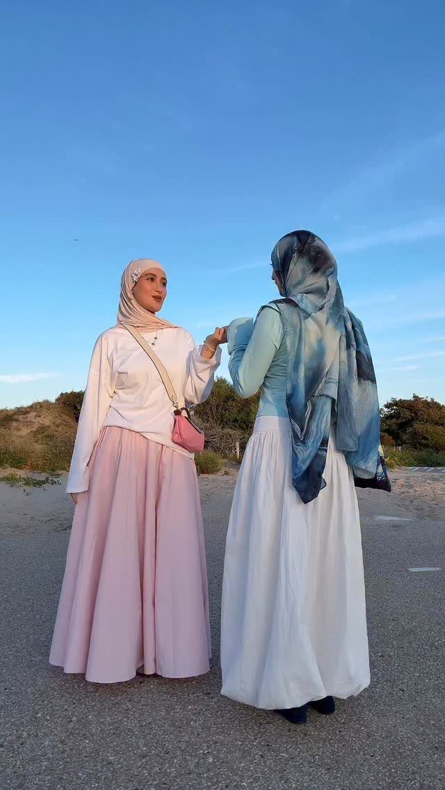 8 Summer Hijab Outfits for Modest, Breathable Style 6 Two women wearing hijabs and long flowing skirts standing outdoors under a blue sky.
