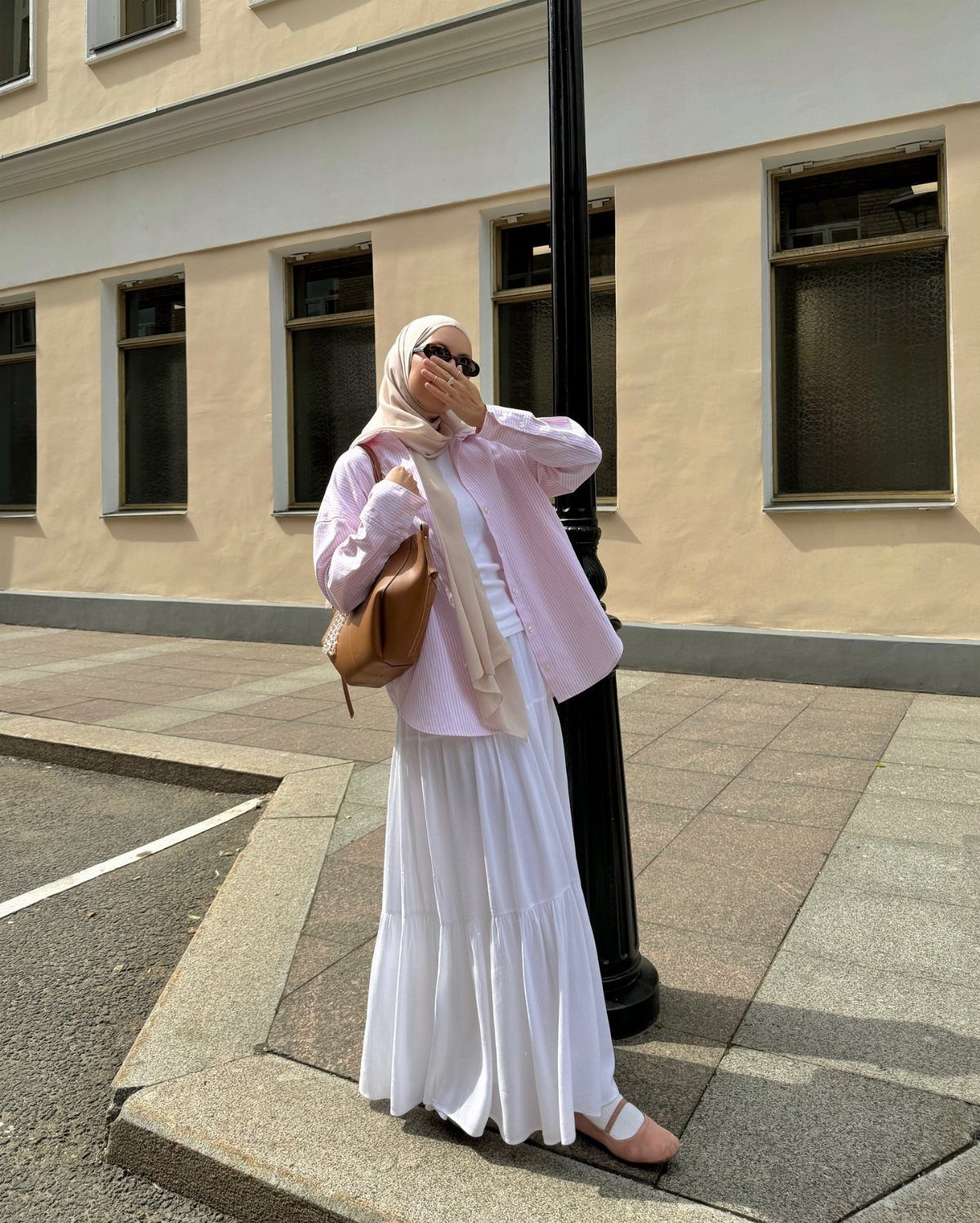 8 Summer Hijab Outfits for Modest, Breathable Style 3 Woman in white hijab, pink button-down shirt, and white tiered midi skirt.
