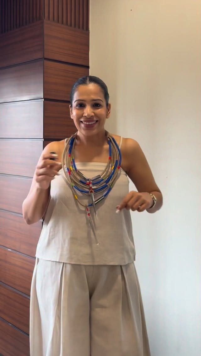 Summer House Outfits: 10 Effortless Ideas for Weekends Away 6 Woman in a beige linen two-piece outfit wearing a colorful beaded necklace.