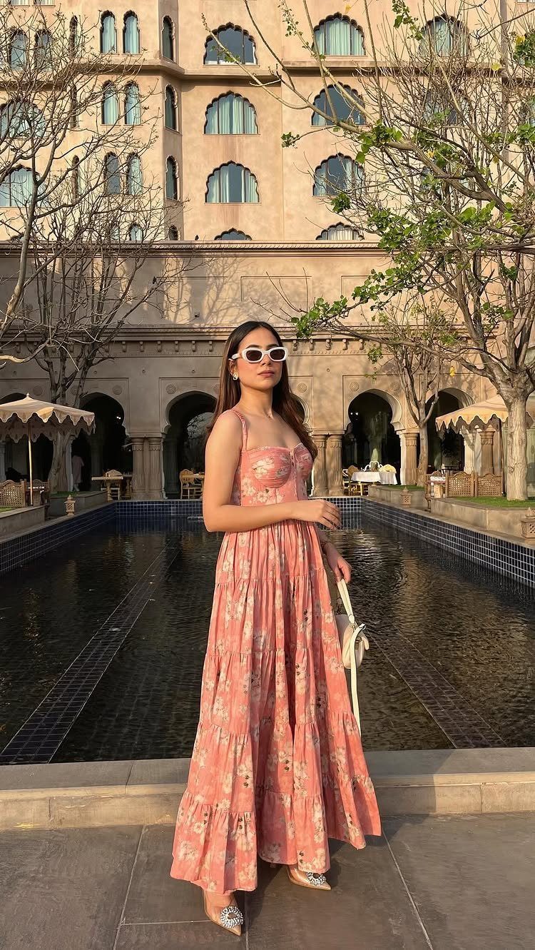 Summer House Outfits: 10 Effortless Ideas for Weekends Away 1 Woman in a pink floral maxi dress and white sunglasses by a reflecting pool.