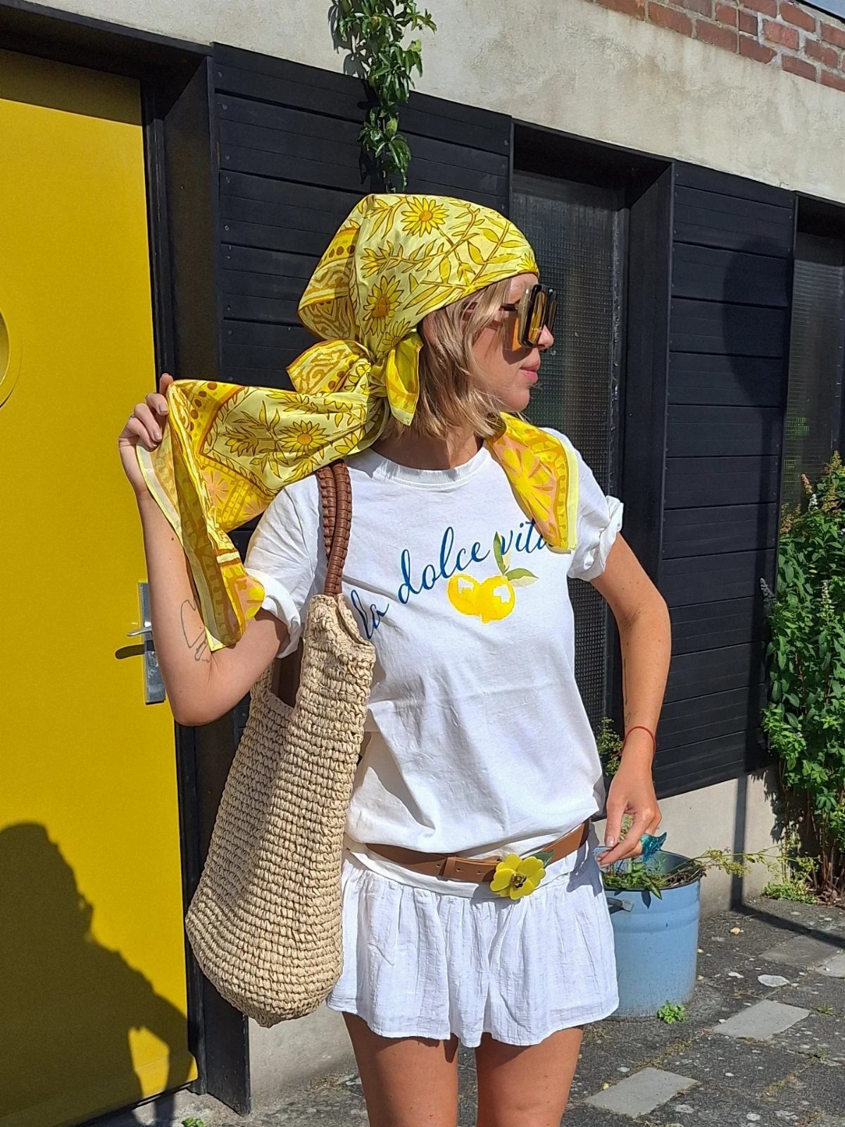 Summer House Outfits: 10 Effortless Ideas for Weekends Away 2 Woman wearing a yellow headscarf and sunglasses with a white summer outfit.