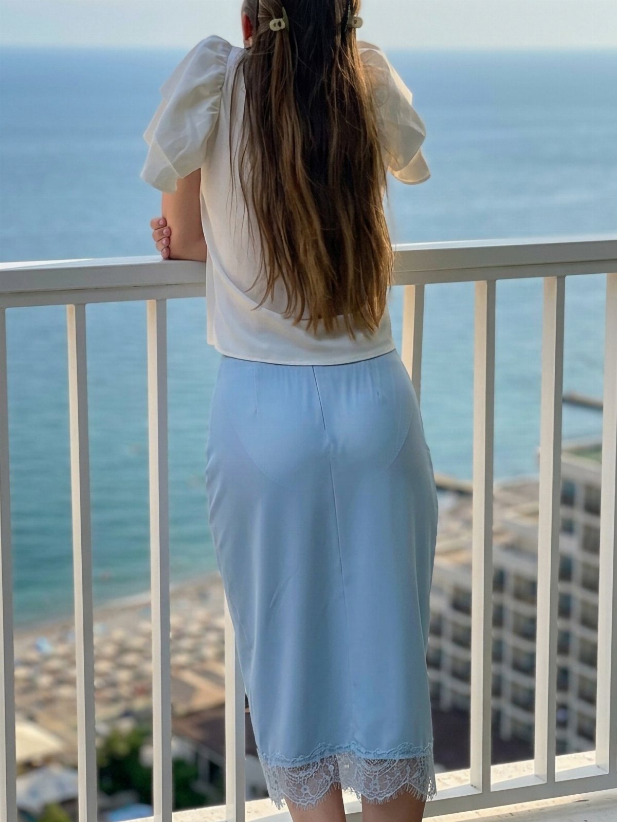 Summer House Outfits: 10 Effortless Ideas for Weekends Away 10 Woman in white blouse and light blue lace midi skirt on a balcony