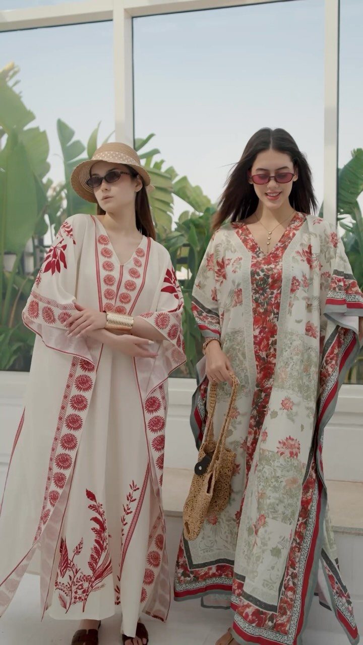 9 Summer Vacation Outfits to Pack for Your Next Trip 1 Two women wearing long white and red patterned kaftans with straw accessories.