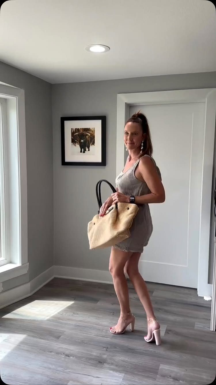 9 Summer Vacation Outfits to Pack for Your Next Trip 8 Woman in a grey dress holding a large straw tote bag in a room.
