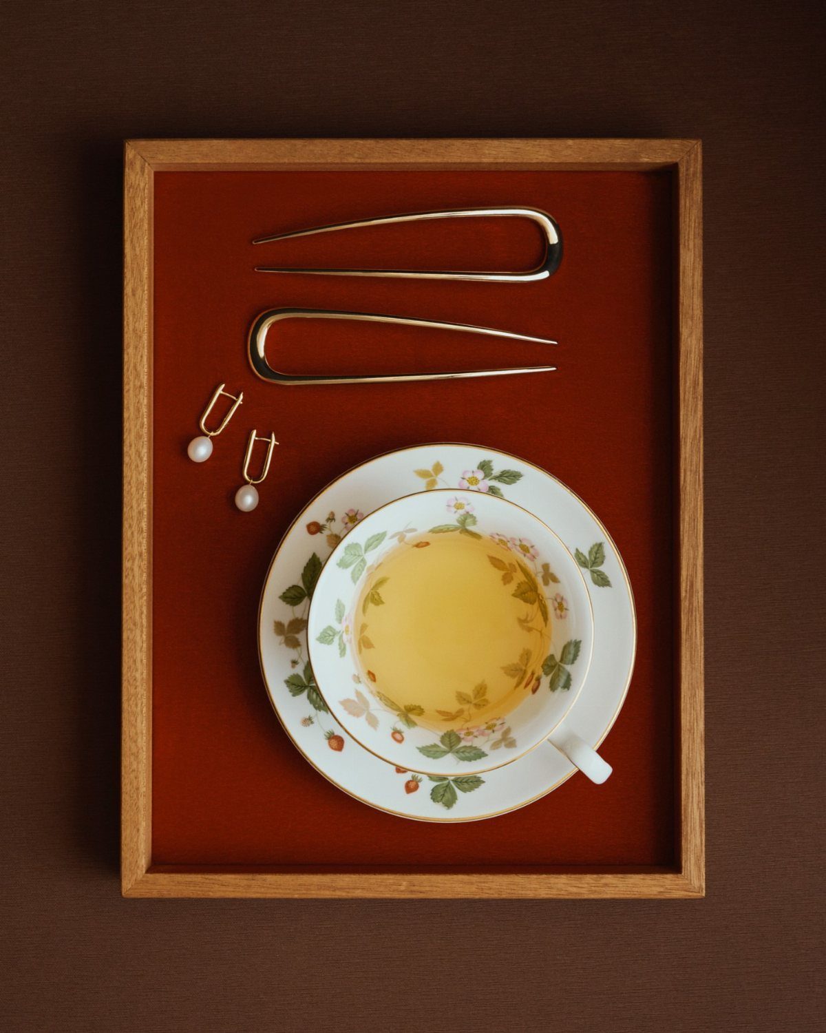 Tea Party Outfits for Adults: 10 Ideas from Garden to High Tea 9 Pearl drop earrings and gold hairpins next to a floral teacup on a tray.