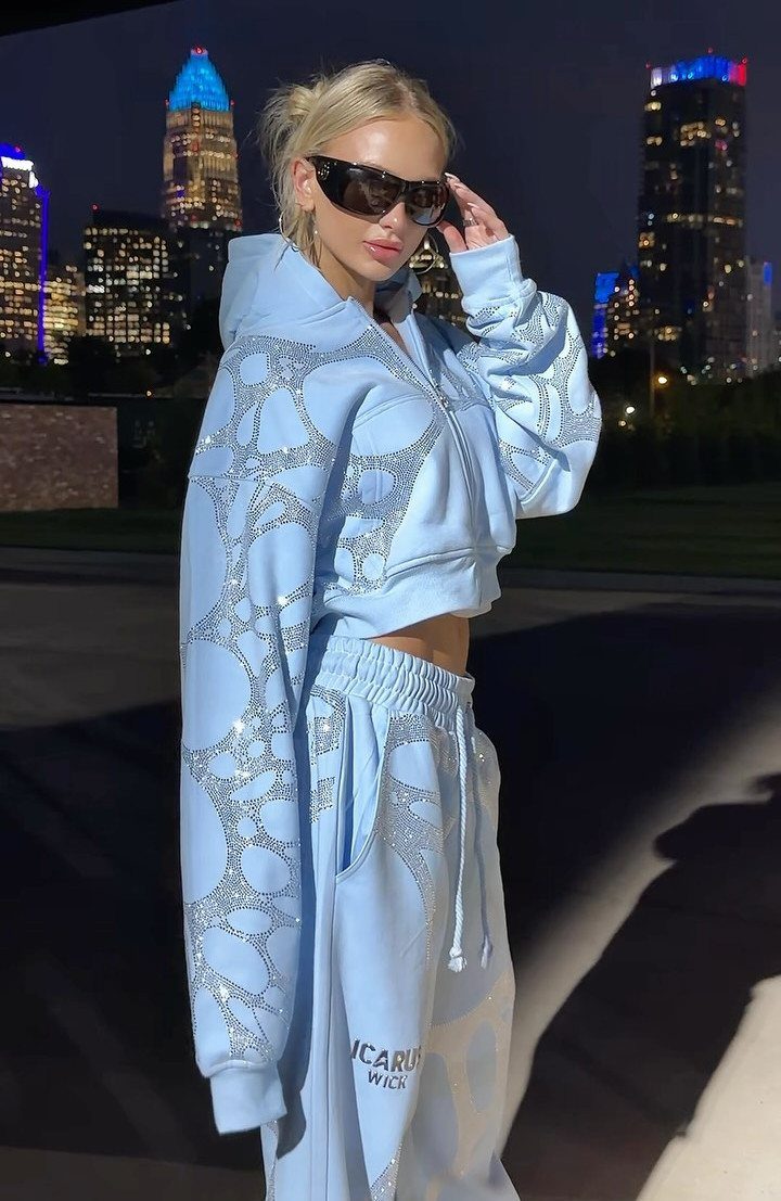 Twice This Is For Outfits: 6 Concert-Ready Looks to Recreate 3 Woman in light blue glittery tracksuit posing against a city skyline at night.