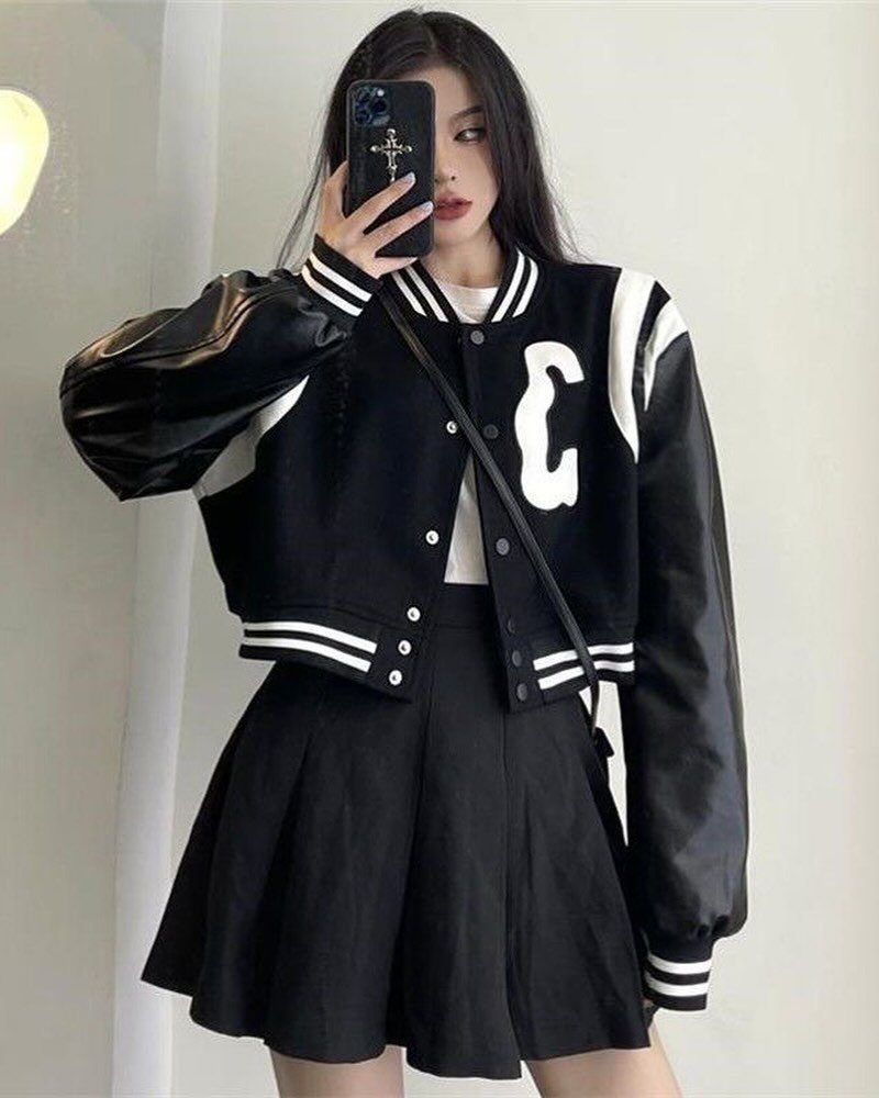 Twice This Is For Outfits: 6 Concert-Ready Looks to Recreate 2 Person in a cropped black and white varsity jacket and black pleated skirt.