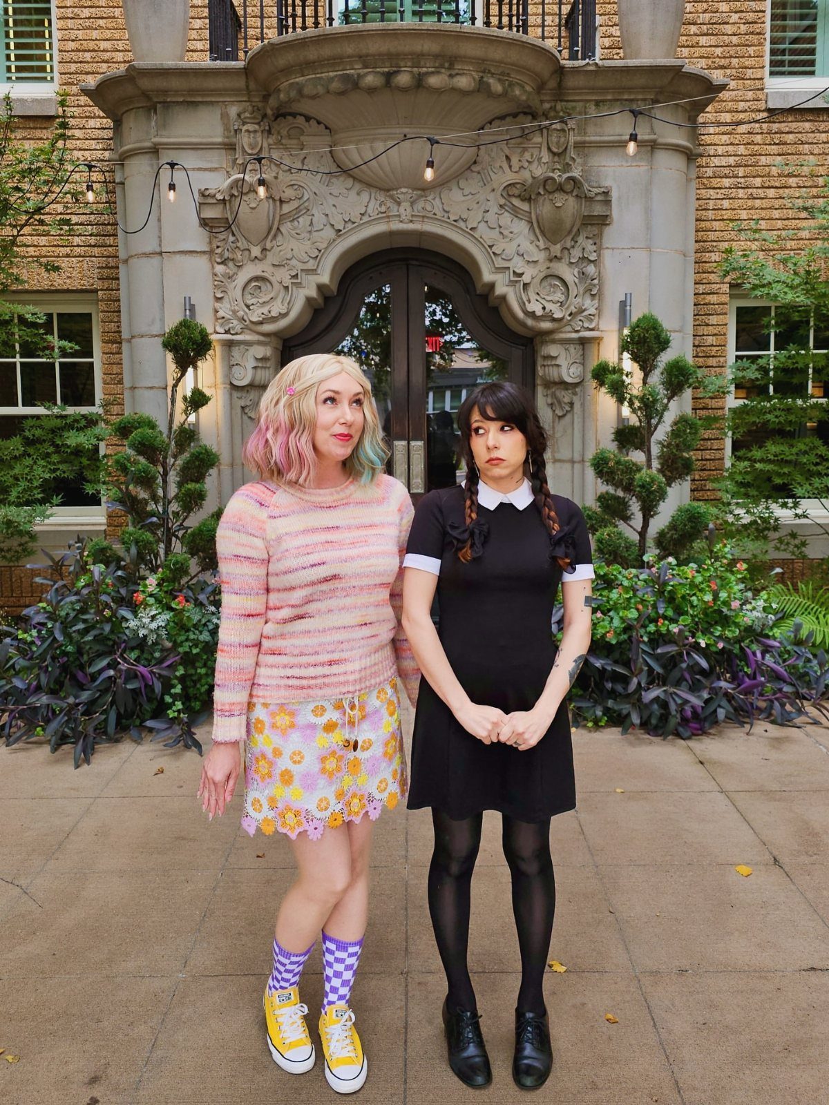 7 Wacky Wednesday Outfits for School, Work & Beyond 4 Two women in eclectic outfits posing before a stone building entrance.