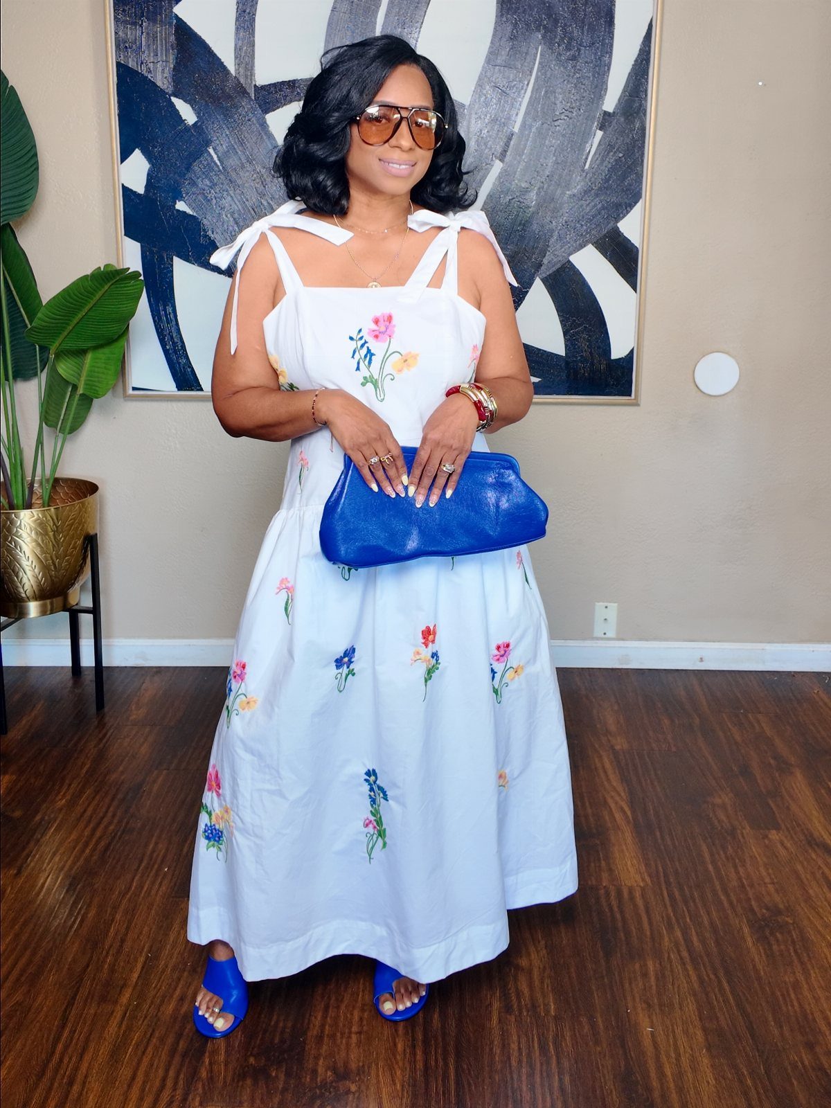 Walmart Spring Outfits: 10 Fresh Ideas for Women This Season 5 Woman in a white floral maxi dress with blue sandals and a blue clutch.