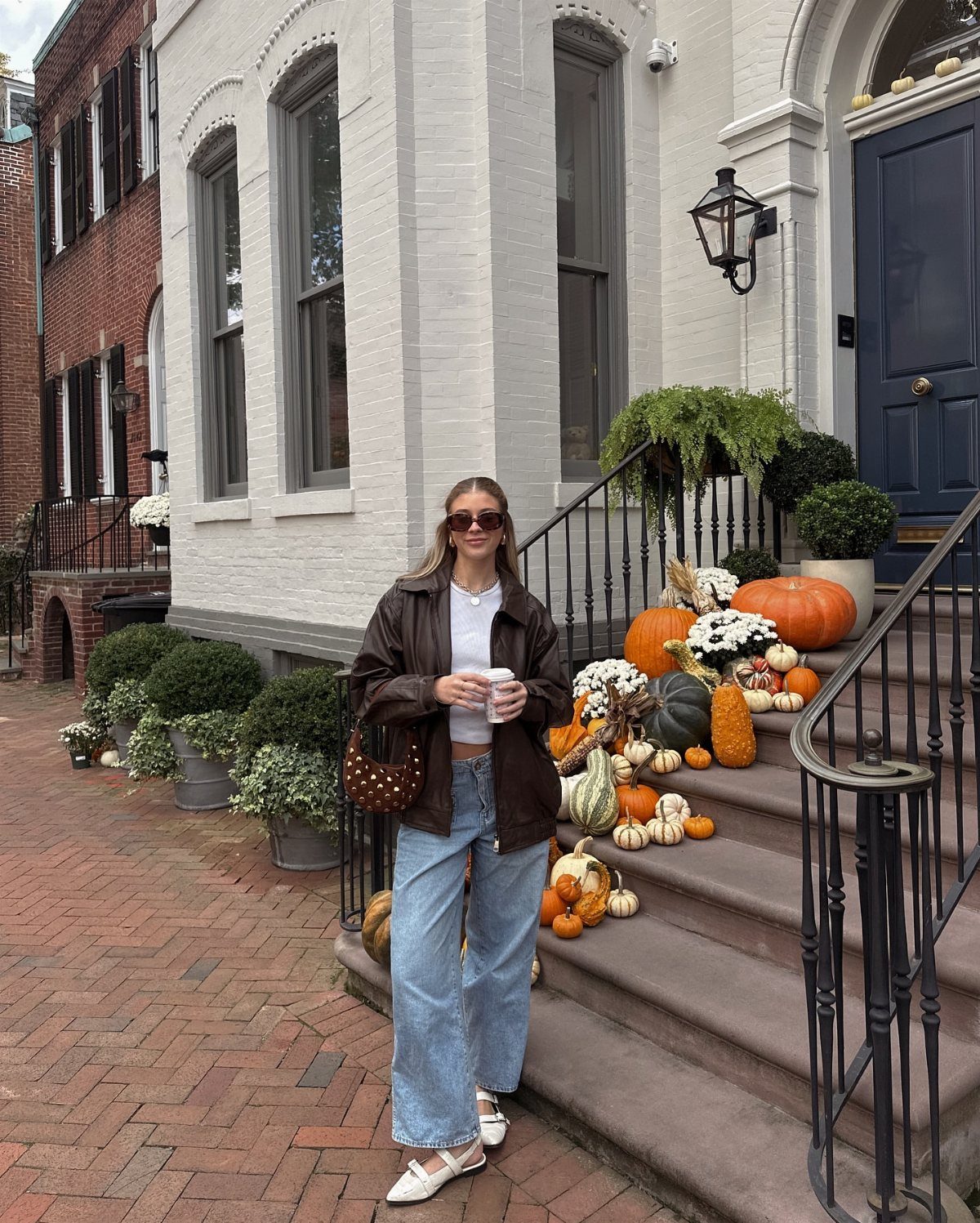 Washington DC Outfits: 11 Stylish Ideas for Your Trip 1 Woman wearing a brown leather jacket and wide leg jeans on a city street