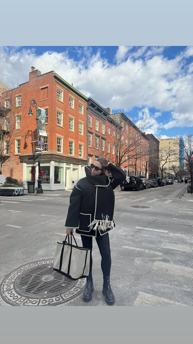 Women's Scarf Coat: 12 Ideas to Try This Season 10 Woman wearing a black coat with a white fringed scarf on a city street.