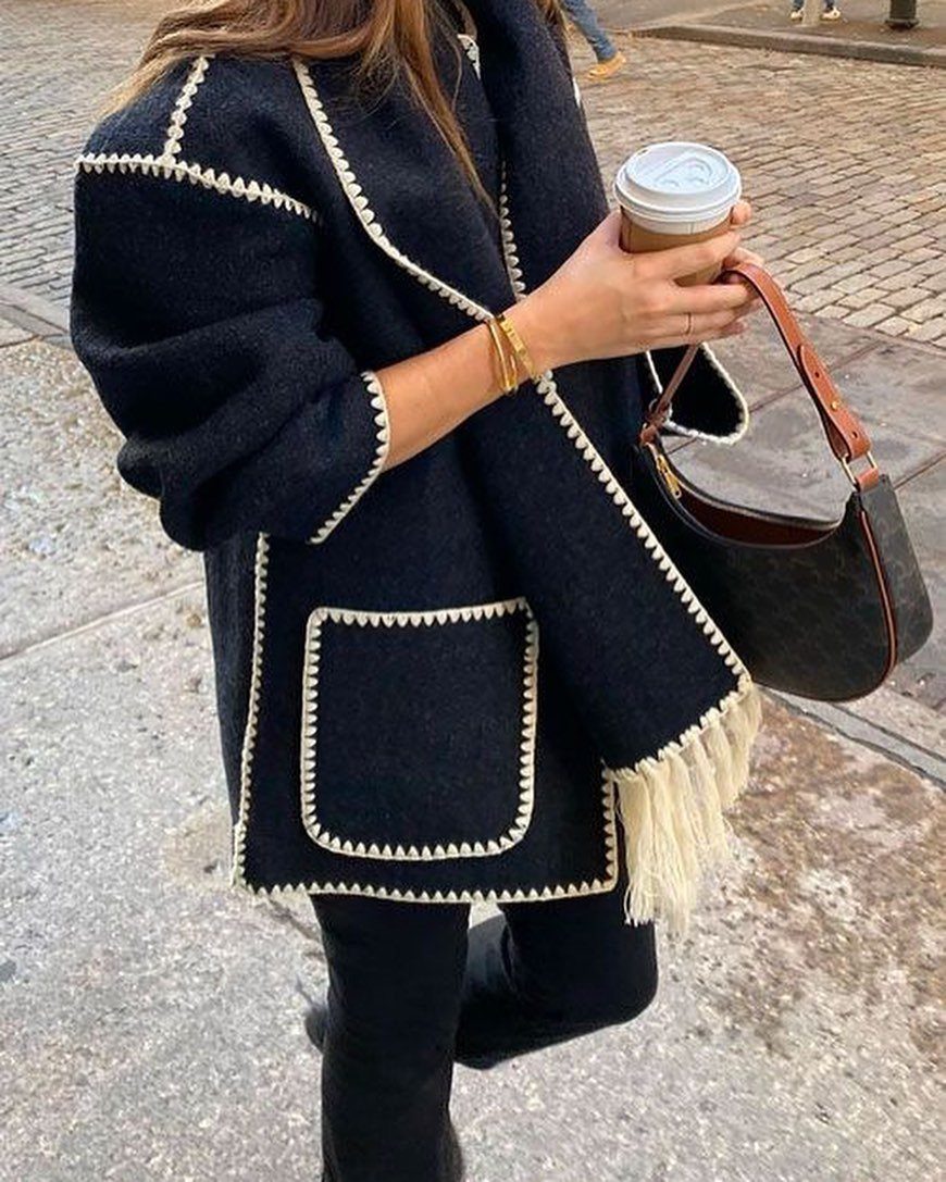 Women's Scarf Coat: 12 Ideas to Try This Season 1 Black oversized wool scarf coat with white contrast stitching and fringe details.