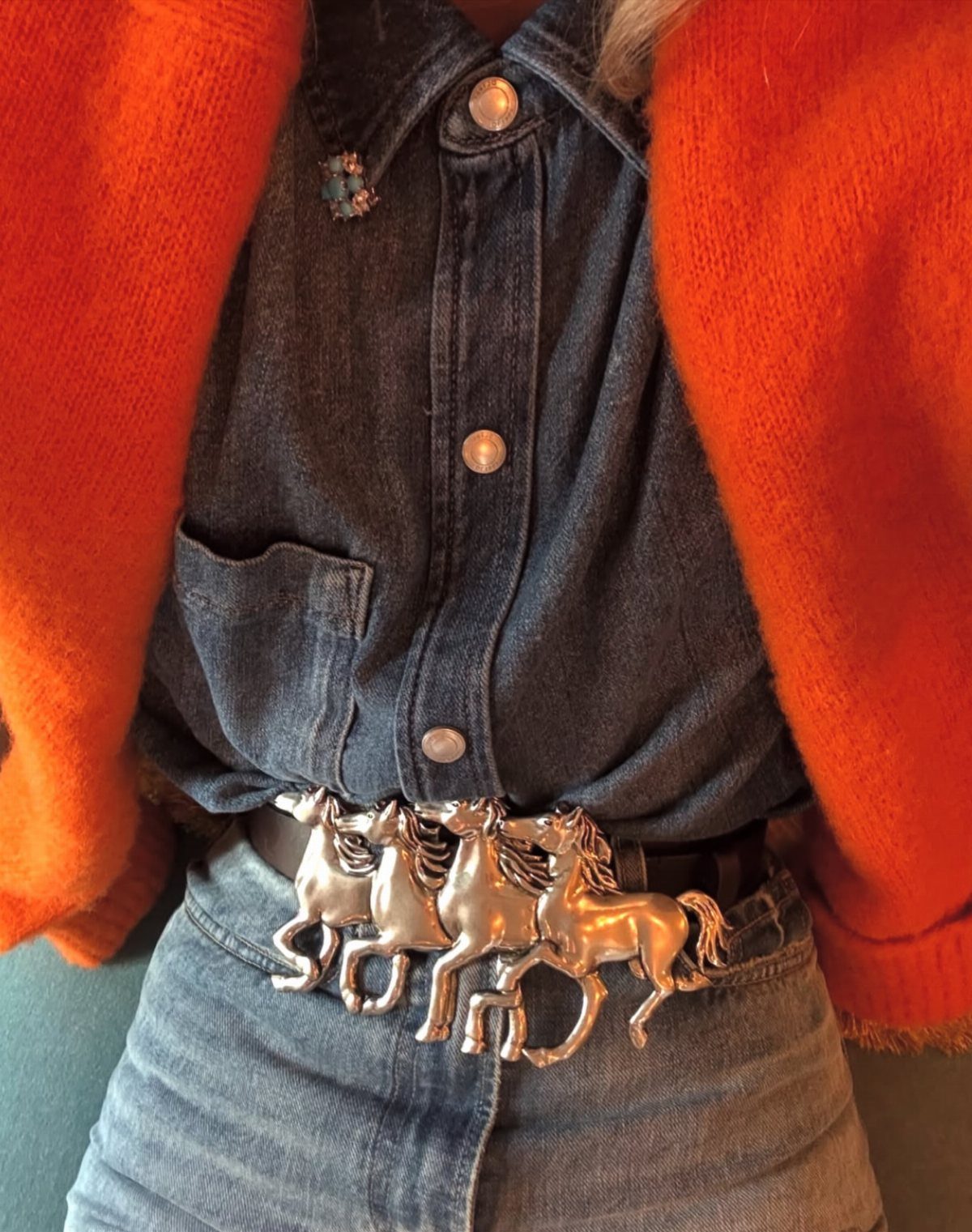 Women's Wild West Outfit Ideas: 9 Styles That Deliver 5 Ornate silver horse belt buckle on a brown leather belt with denim clothing.