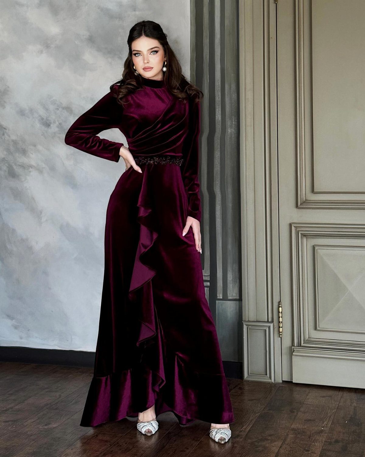 13 Zara Holiday Outfits for Parties and Celebrations 11 Woman wearing a long-sleeved burgundy velvet gown with a ruffled front and sparkling belt.
