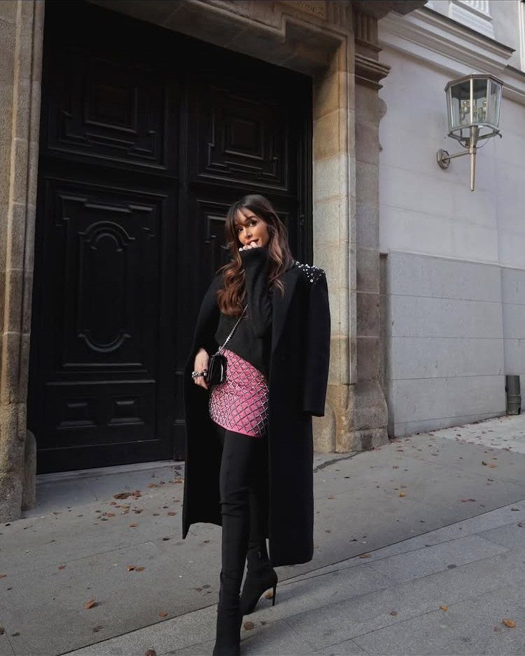 13 Zara Holiday Outfits for Parties and Celebrations 9 Woman wearing a long black coat and pink sequined mini skirt outdoors.