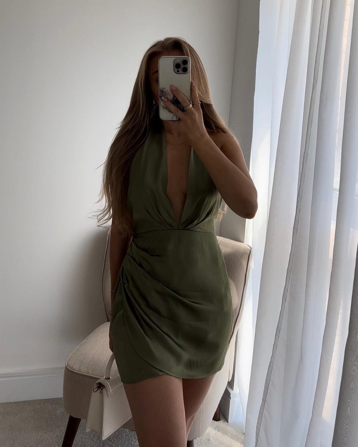 13 Zara Holiday Outfits for Parties and Celebrations 3 Woman wearing an olive green satin effect mini dress in a bright room.