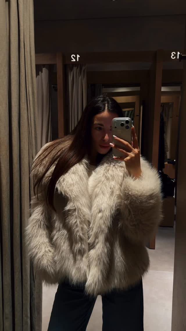 13 Zara Holiday Outfits for Parties and Celebrations 6 Woman wearing a short cream faux fur coat in a dressing room mirror selfie.